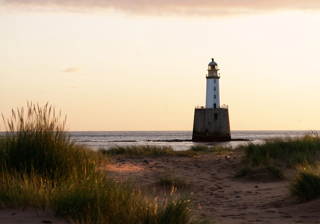 Rattray Head Lighthouse at sunrise seen through the sand dunes and dune grass