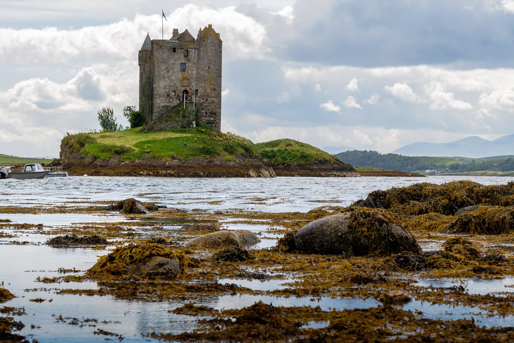 castle on an islet with seaweed in the foreground water