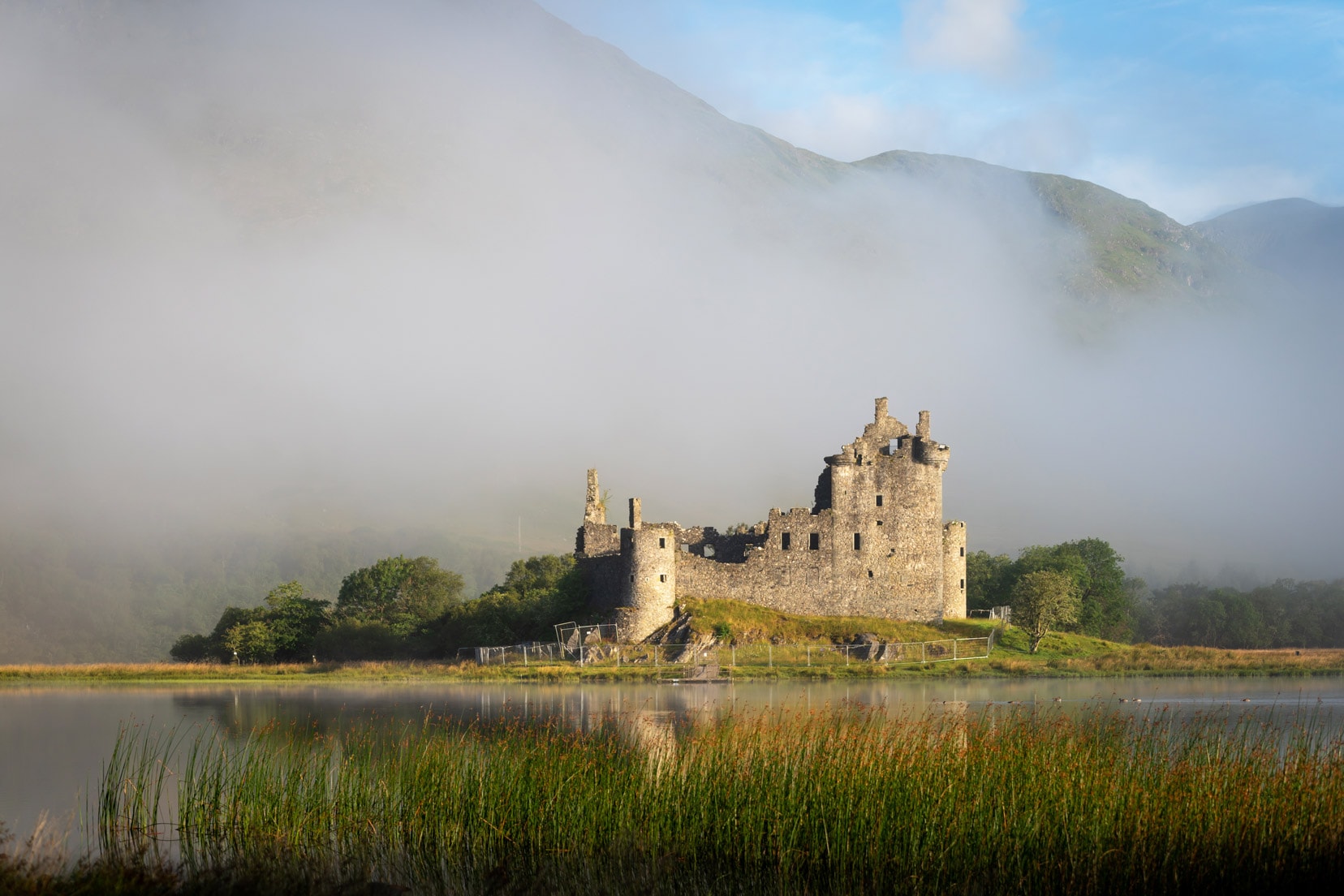 castle seen in the fog over a loch