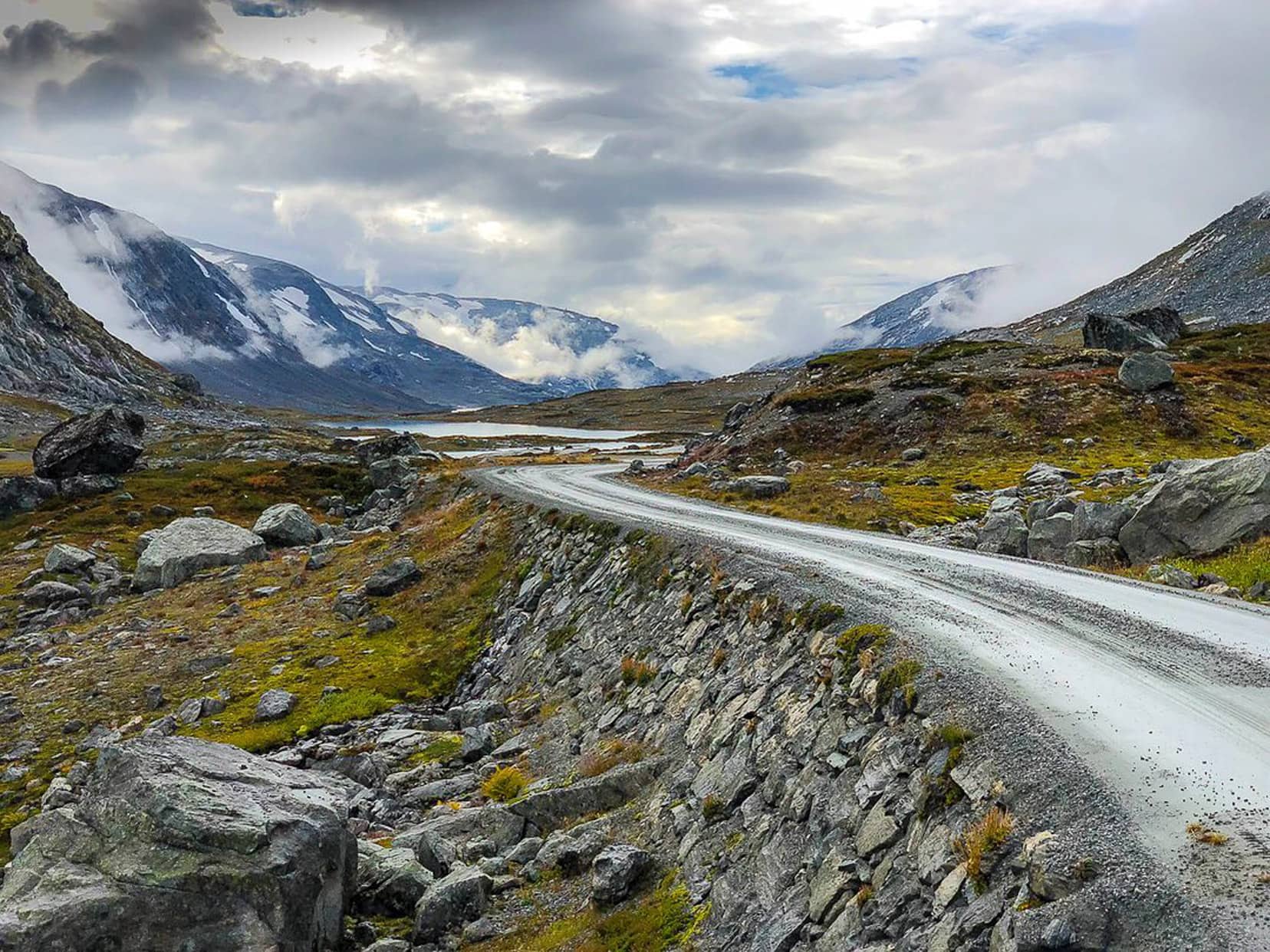 scenic road through snowy covered mountains with cloudy sky