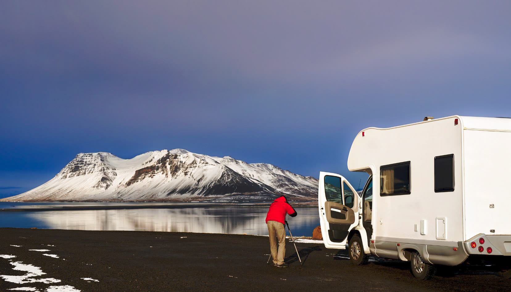 campervan-on-black-sand with snowy mountain in background during a road trip