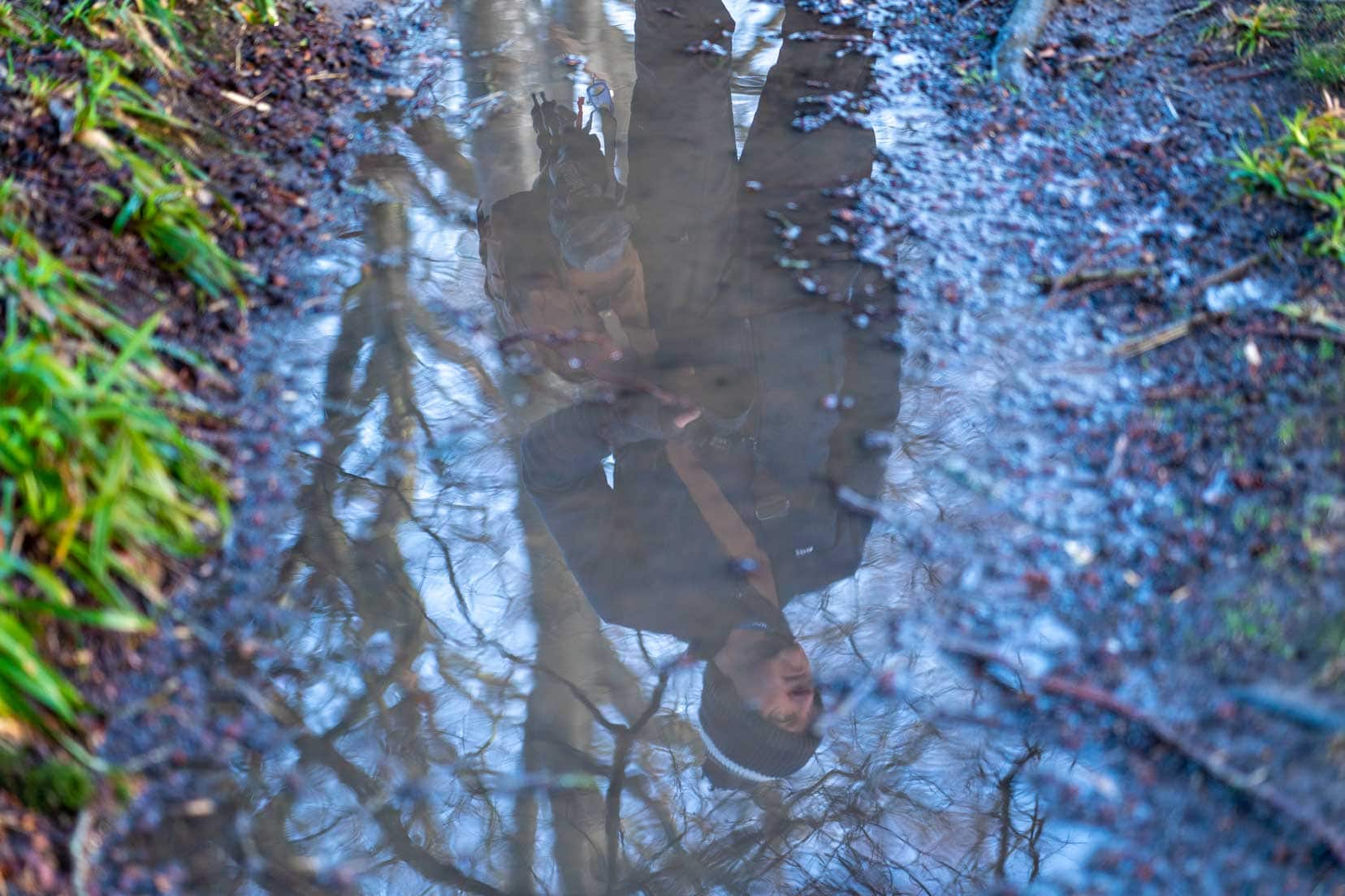 Man reflected in a puddle of water — Using wet weather to create reflections 