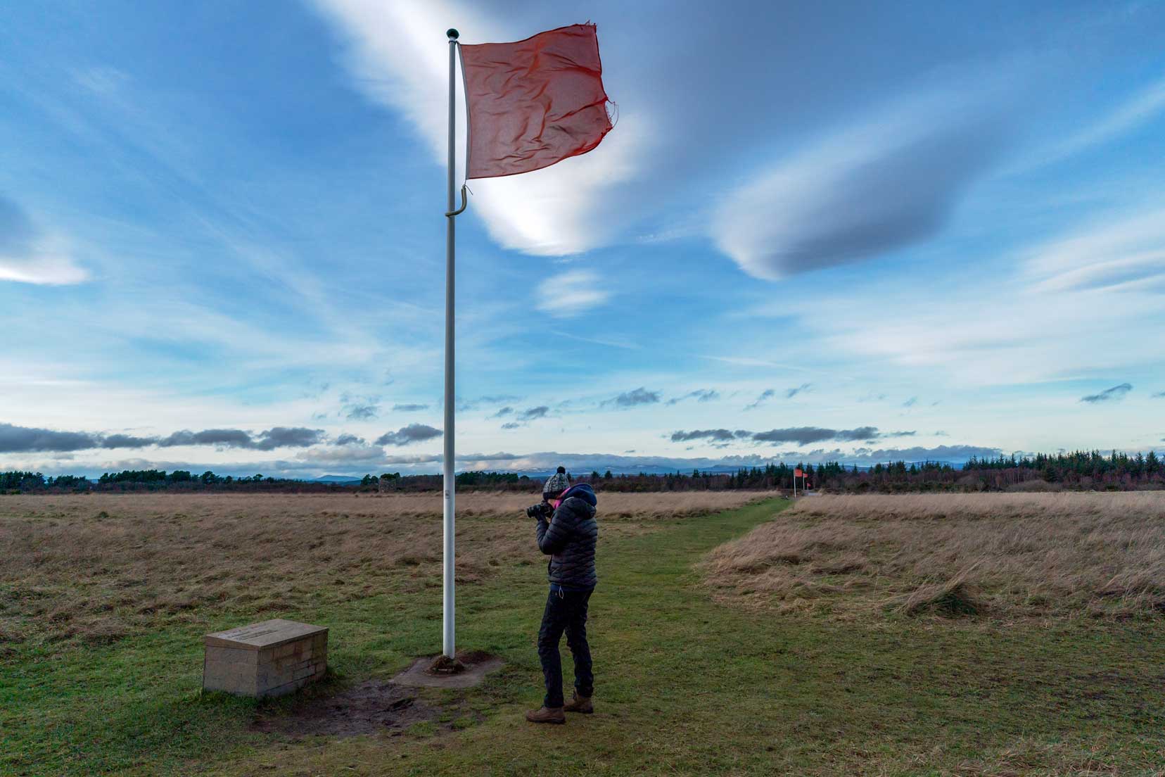 Culloden battlefield with flag showing the line of defence and shelley taking a phot of an information board