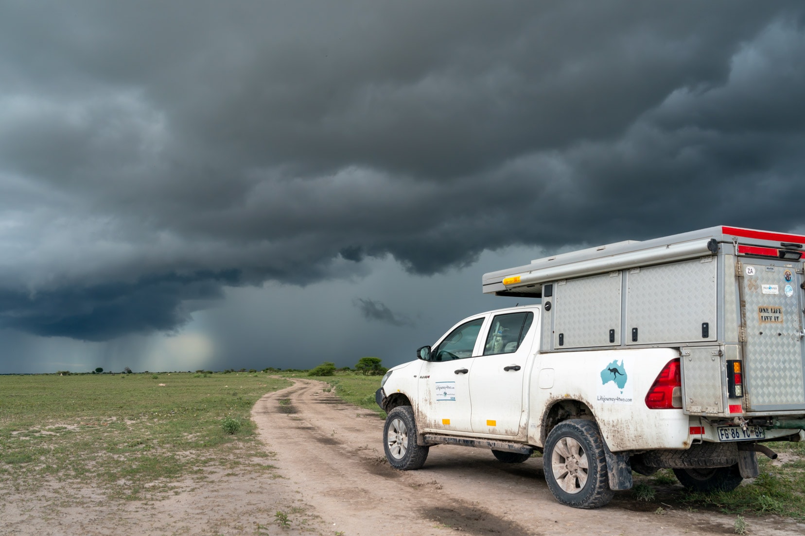 Intense summer thunderstorm bears down on a 4x4 on an open plain on our overlanding Botswana trip