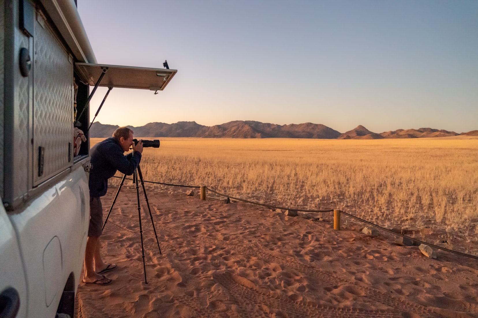 lars with camera taking photos fo the landscape beside the camper at Kanaan desert retreat namibia