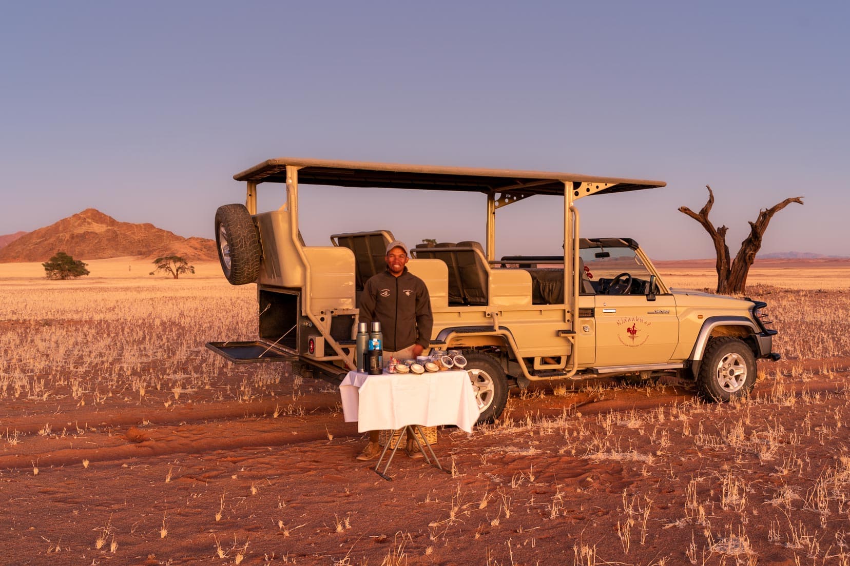 sunrise-game-drive-snacks on table and vehicle and guide stood behind