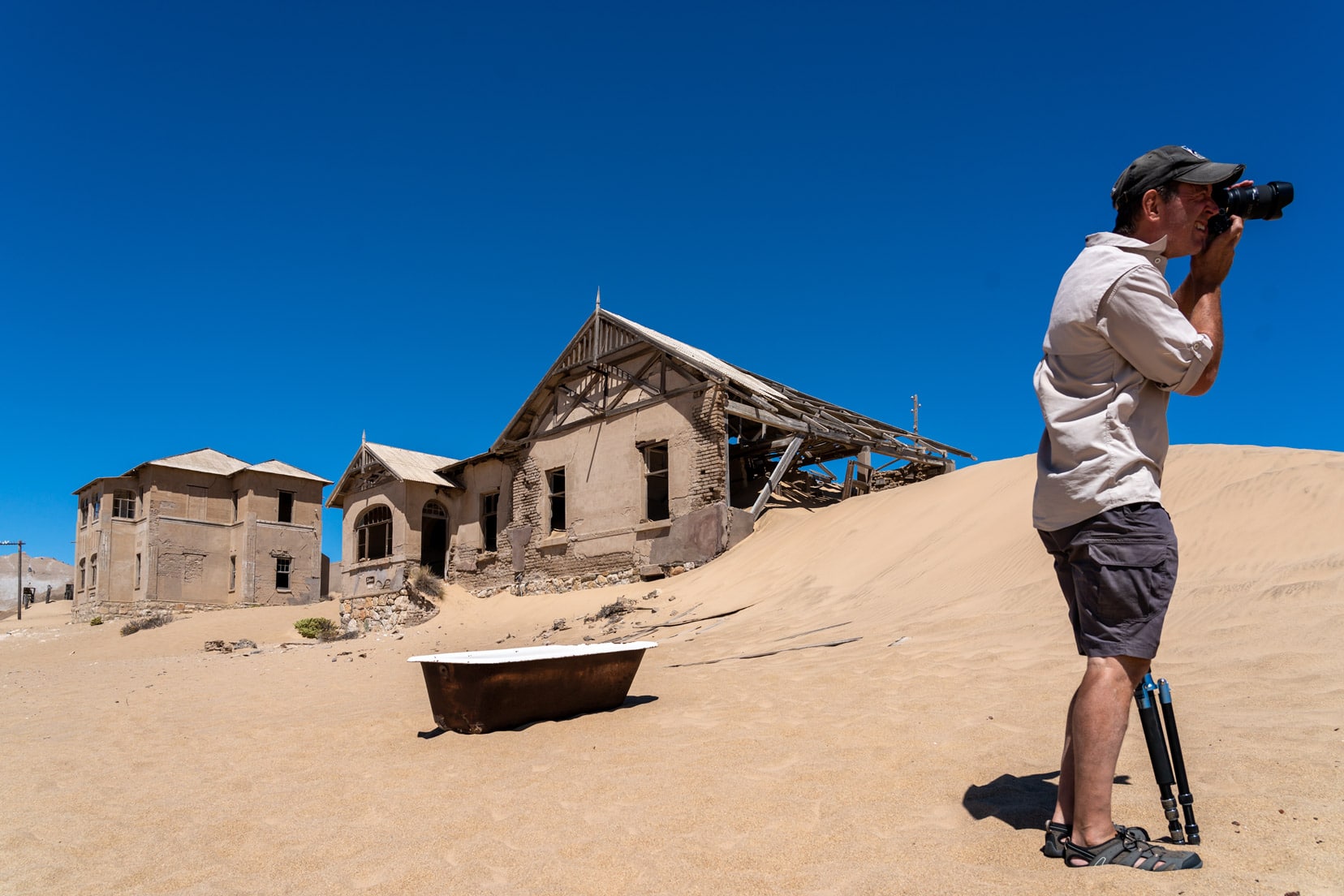 iron bath on the sands at Kolmanskop ghost town in front of decaying houses