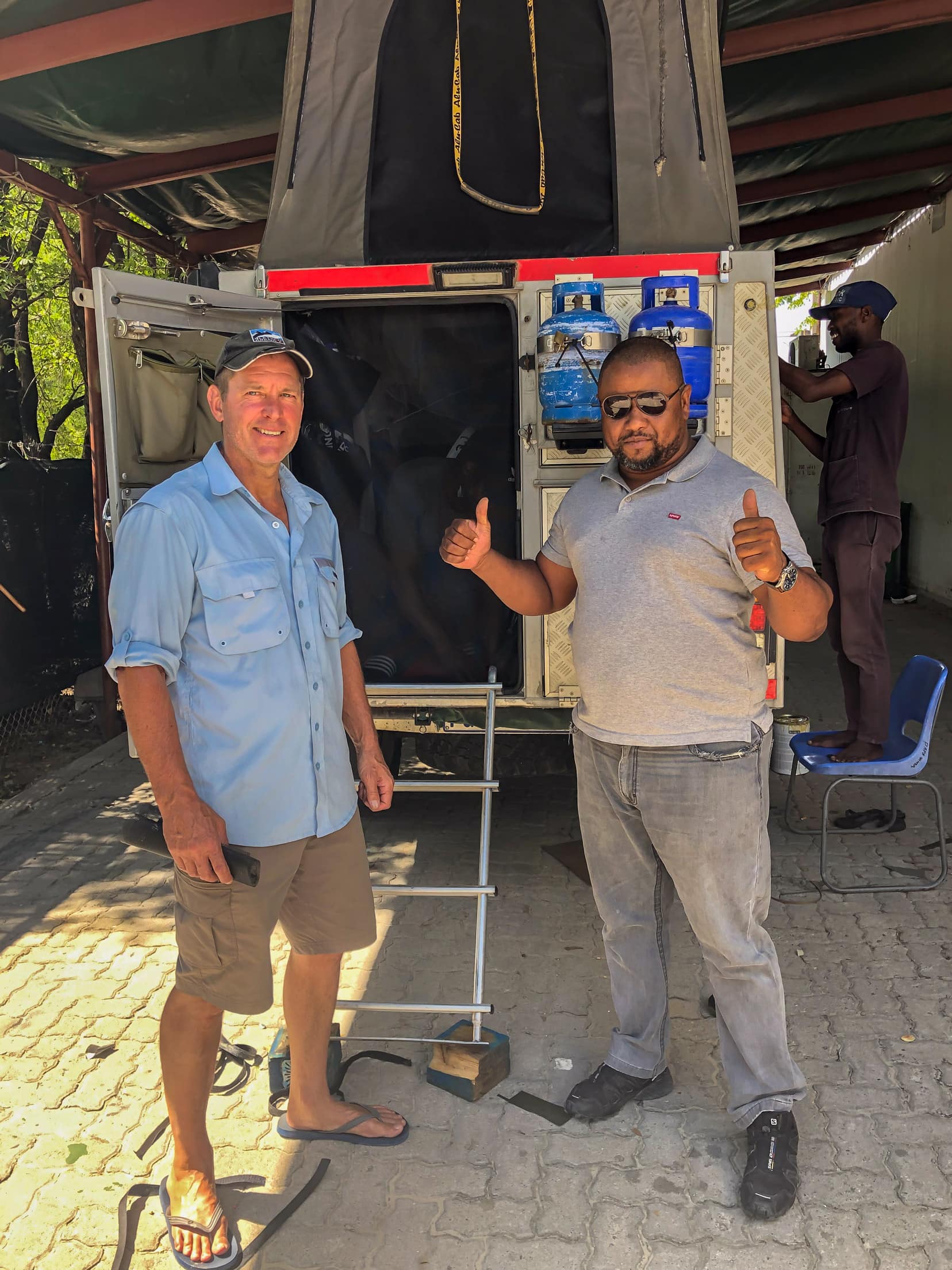 2 men in front of a Hilux bush camper in Maun, Botswana having some insect screens added 