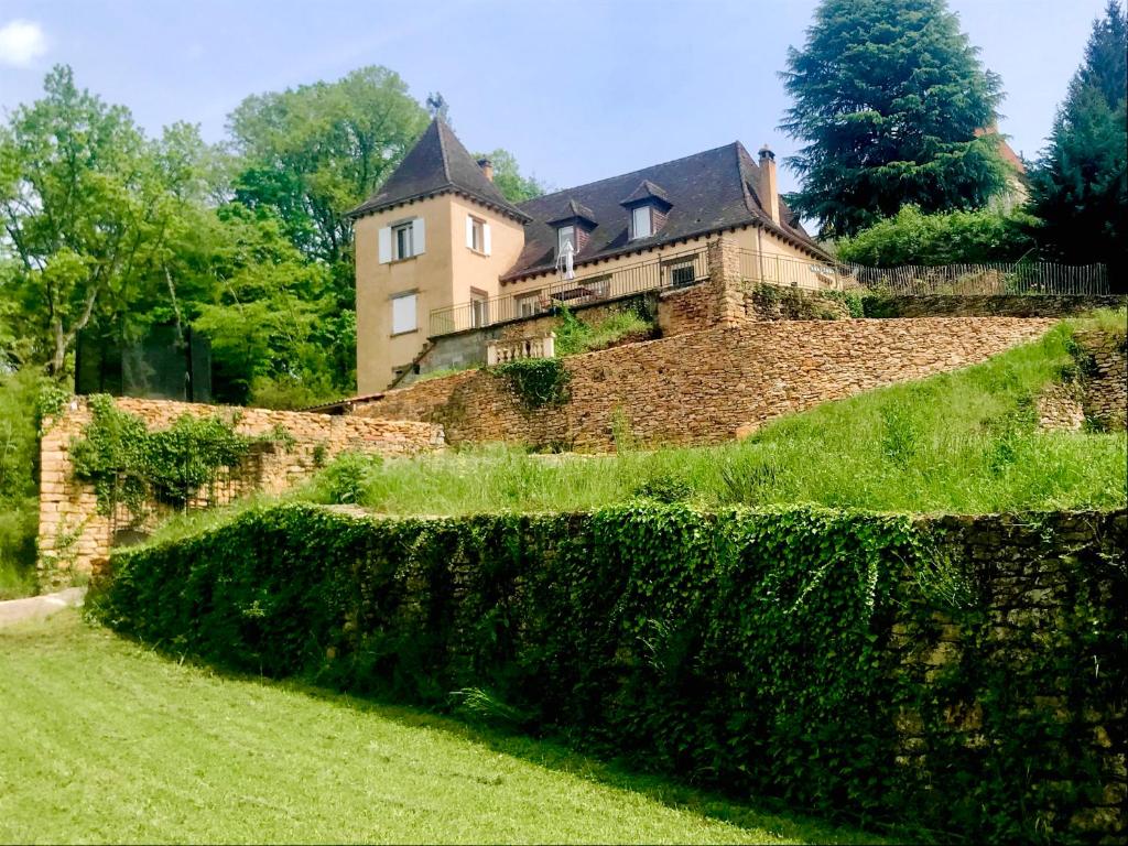 stone building visible behind a wall and green bushes