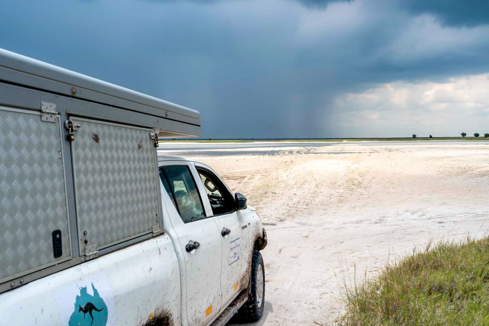 4x4 stopped in front of a salt pan with thunderstorm on the way