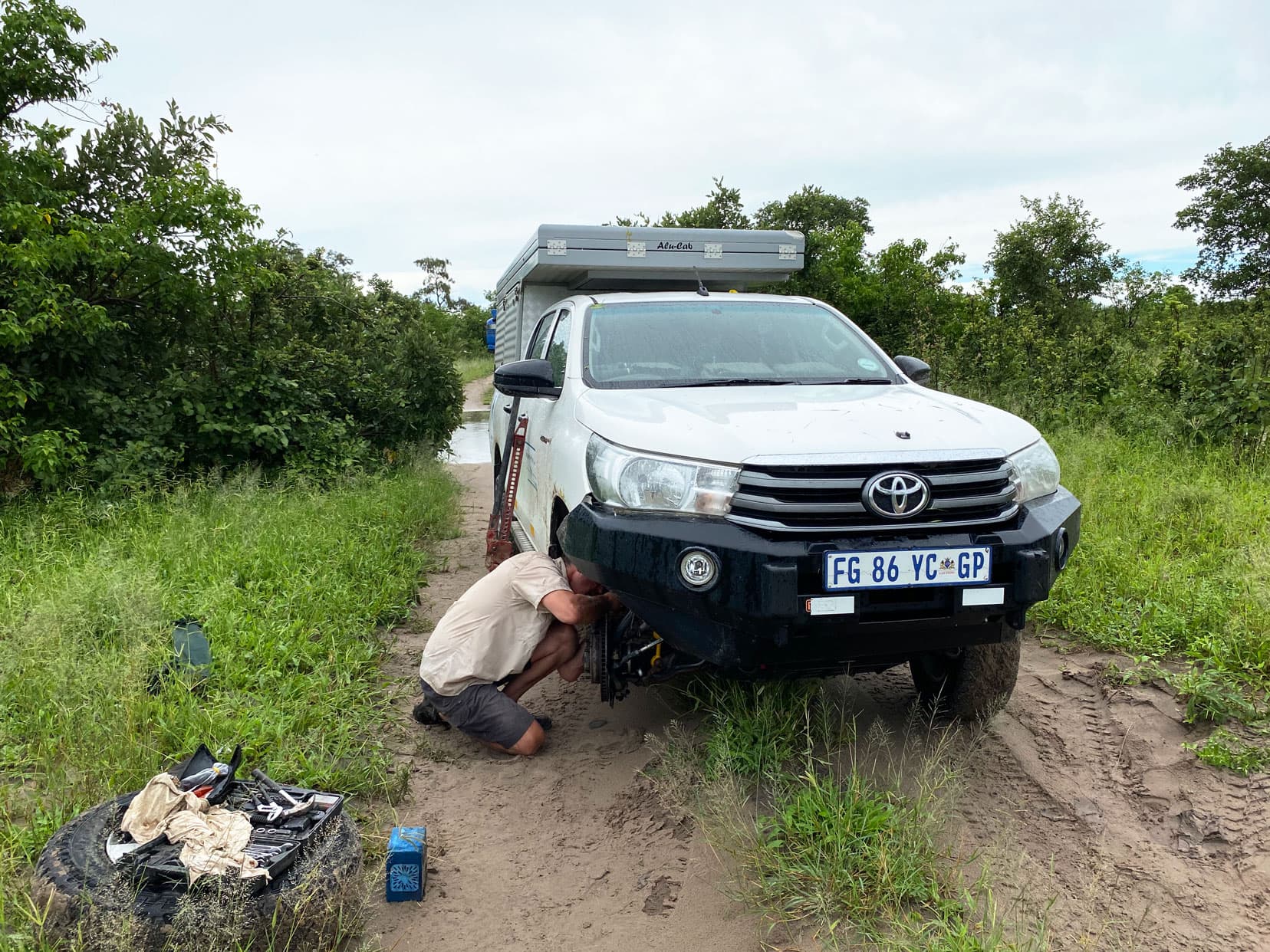 Lars taking wheel off on a muddy track with bushes around