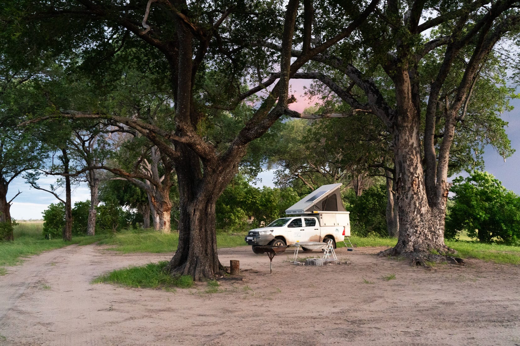 Moremi-game-resrve-Campsite-at-Xakanaxa campsite - our camper with roof top tent under two shady trees with sand around it