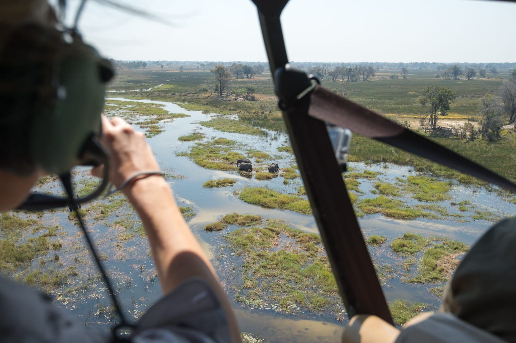 person taking photos from a helicopter with view over the okavango river 