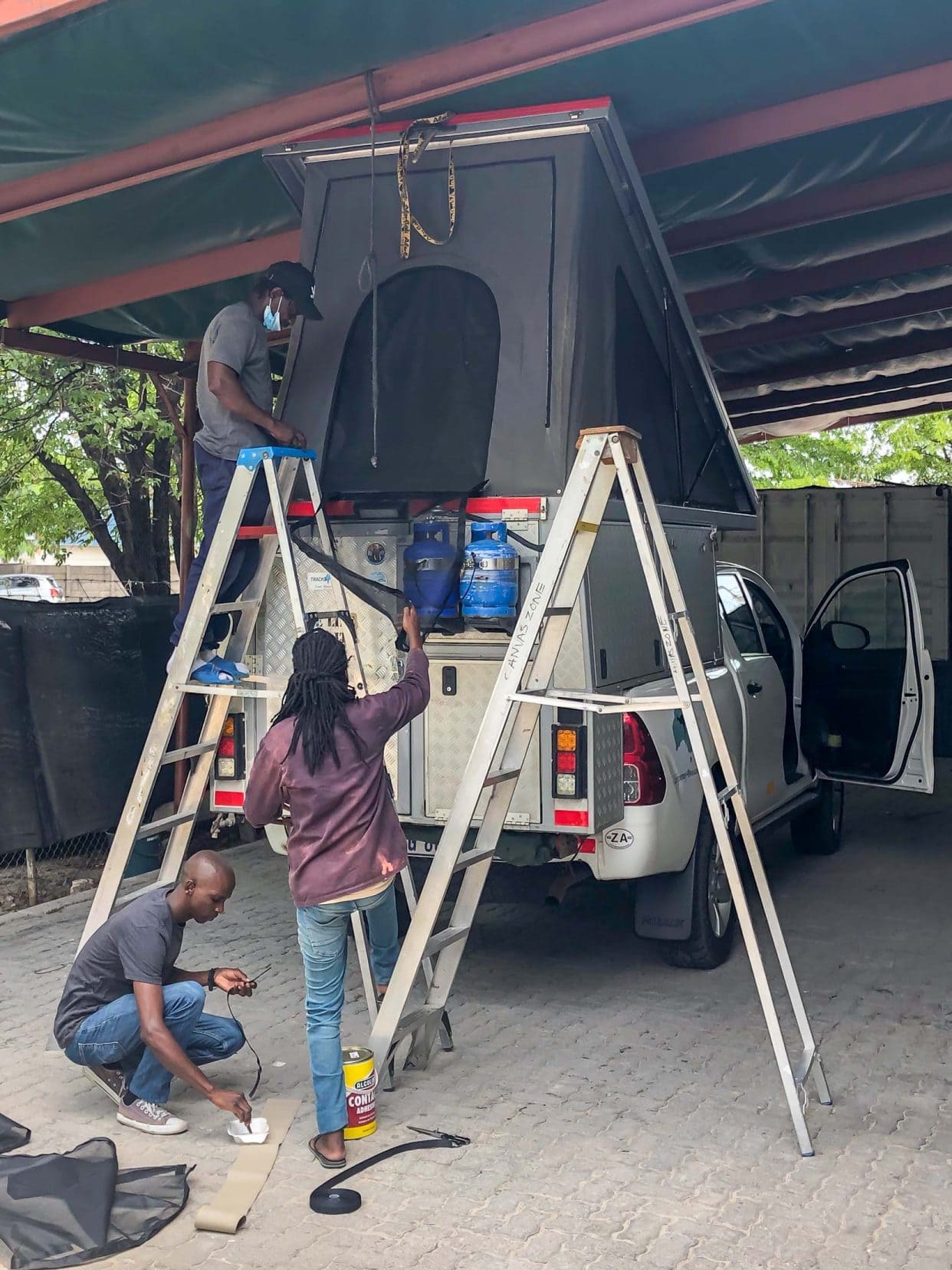 men fitting insect screens to a 4x4 rooftop tent