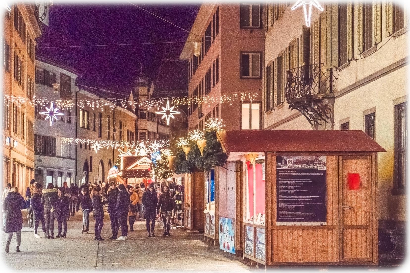 Chur town with christmas lights strung across the street with wooden christmas chalet stalls and people wandering about