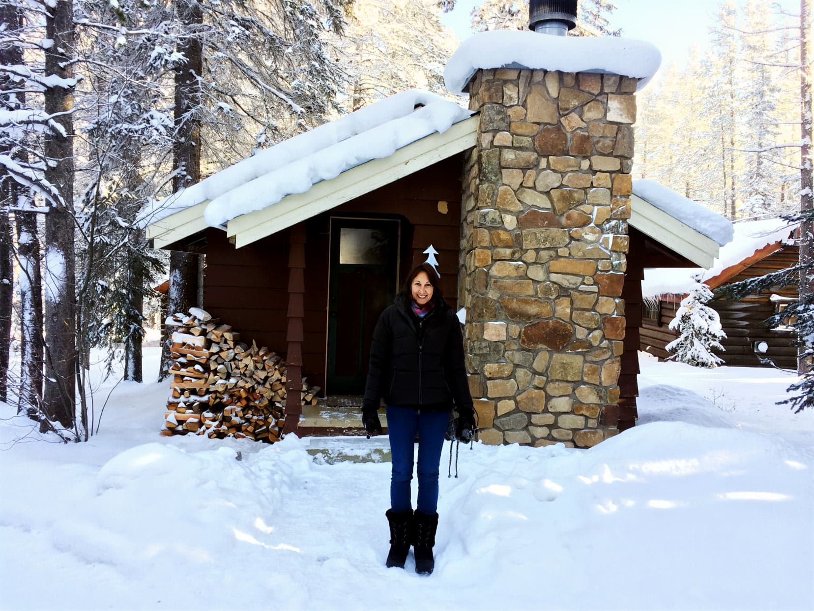 Shelley stood outside the log cabin in the snow Banff National Park, wearing snow boots.