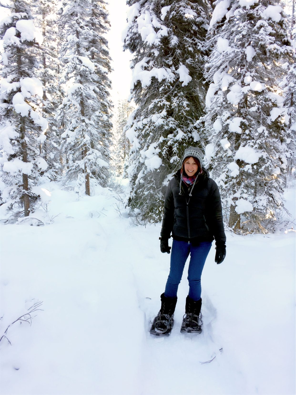 Shelley in snowshoes in the snow surrounded by snowy pine trees