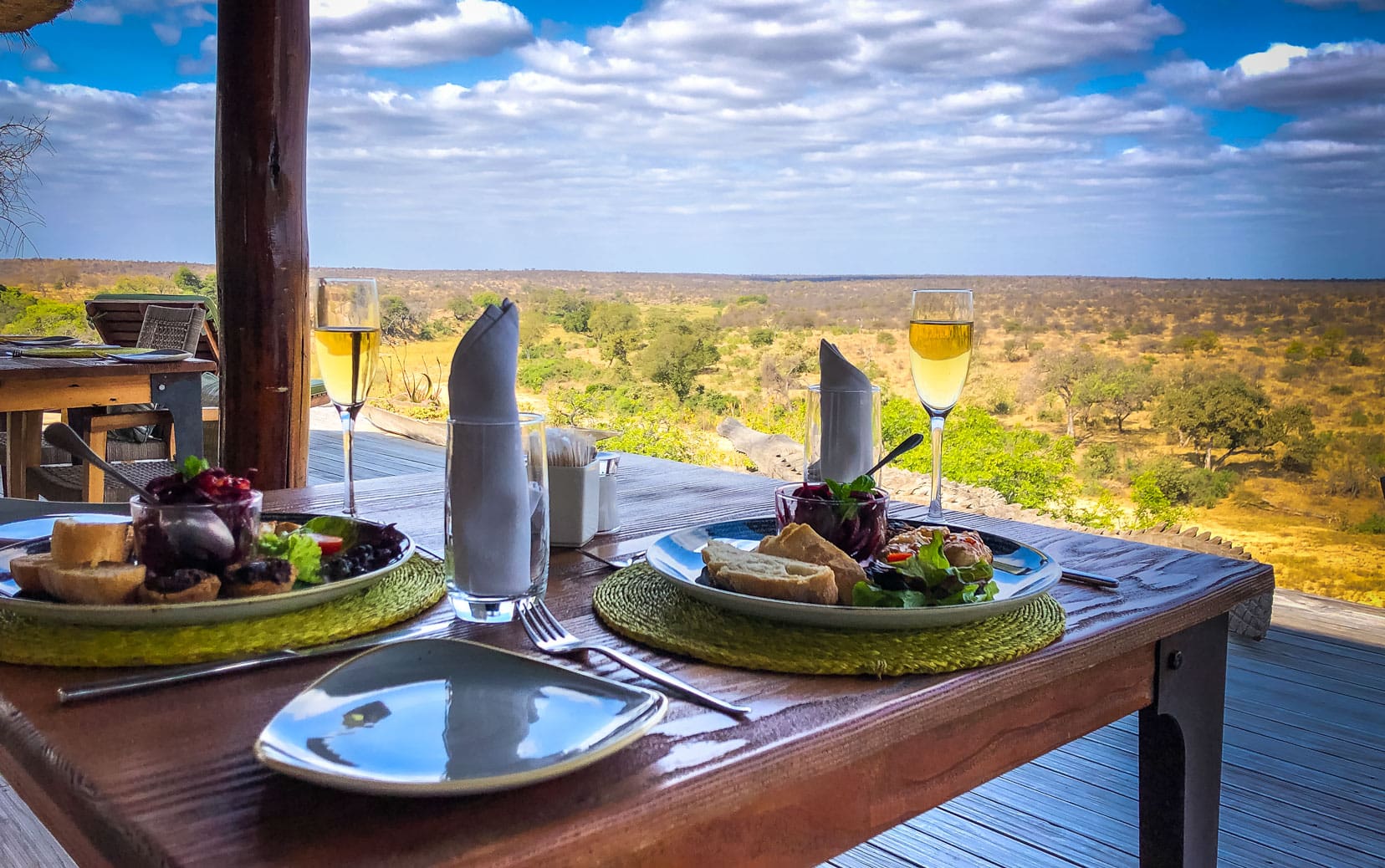 Ding Table with plate of food and glass of wine with the african bush in the back ground at Klaserei drift  