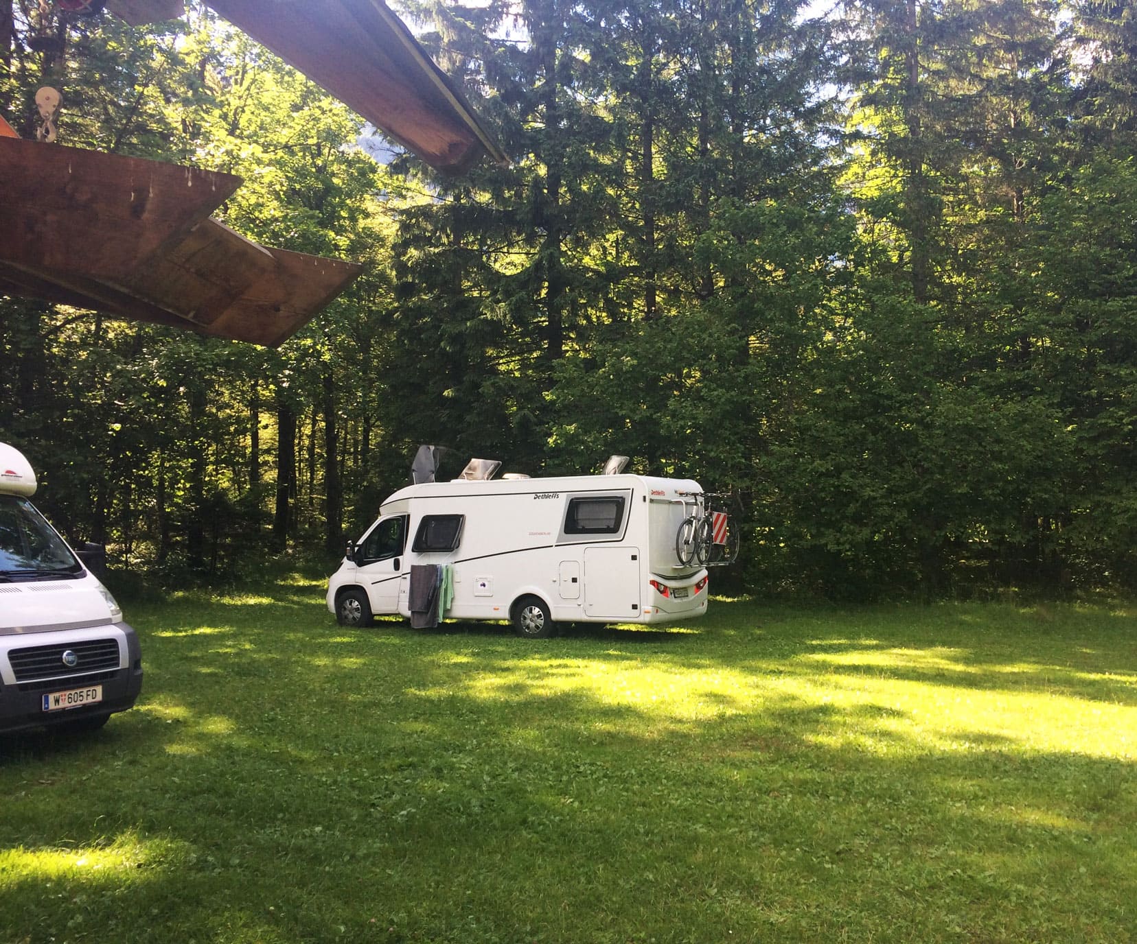 Campervanning-in-Europe motorhome-parked-in-Slovenia on green grass and tall pine trees 