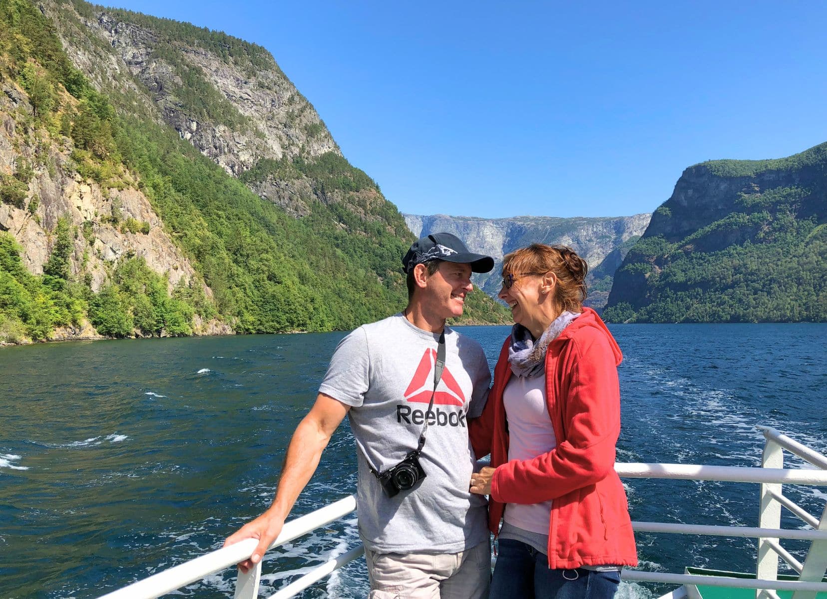 Lars and Shelley on a boat laughing with fjord and mountain the background