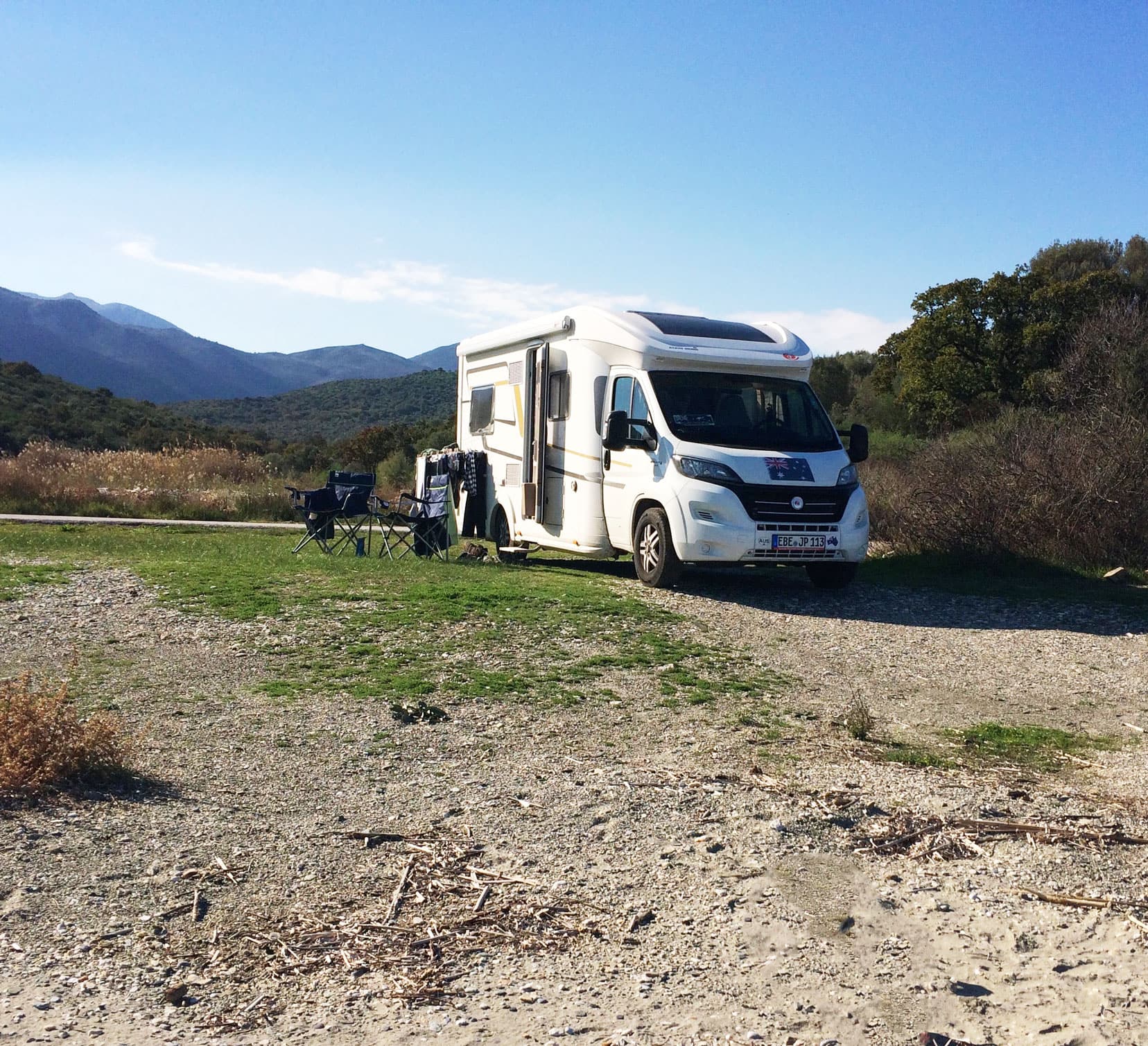 Motorhome parked on grass with camp chairs and washing on a dryer