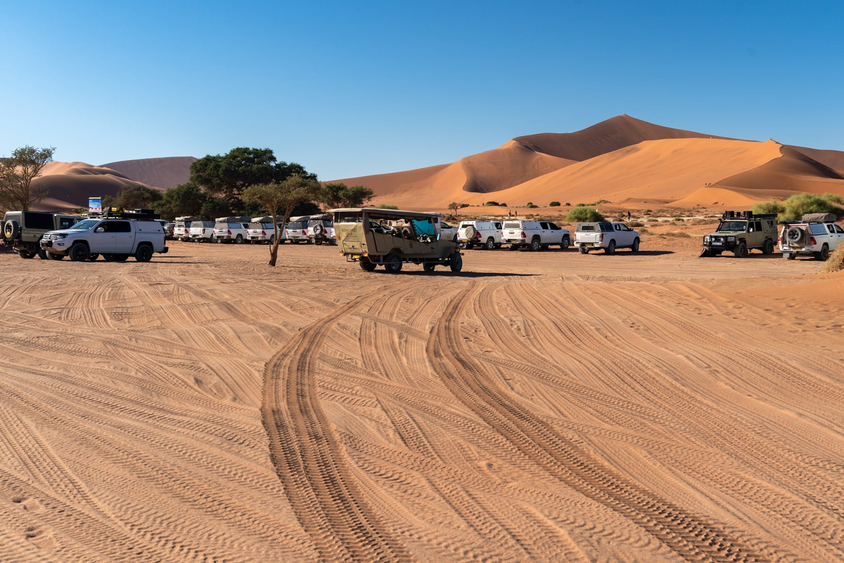 Sossusvlei car park with shuttle and cars and Big daddy dune in the background