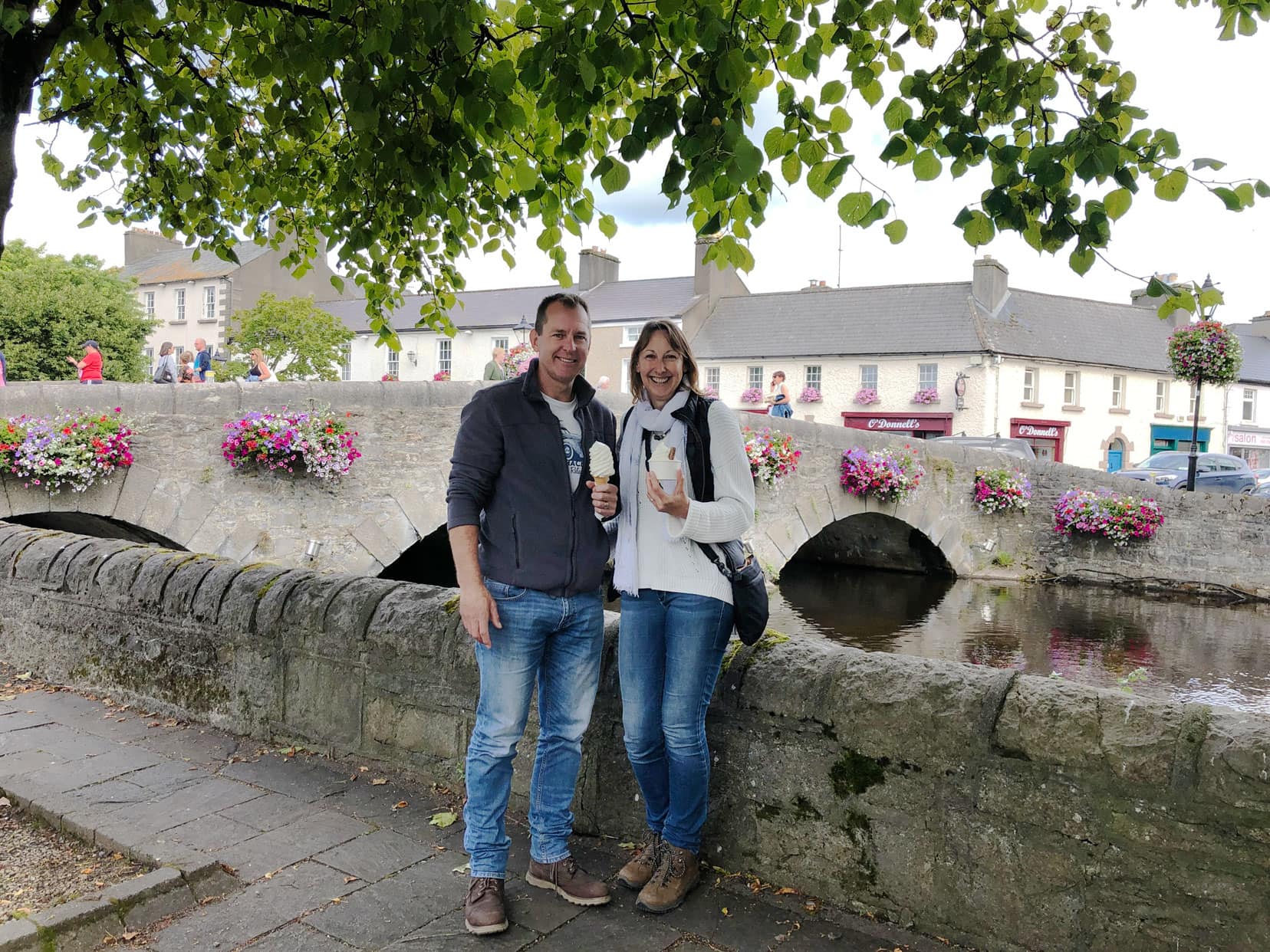 ars and Shelley stood by bridge adorned in flowers eating icecream