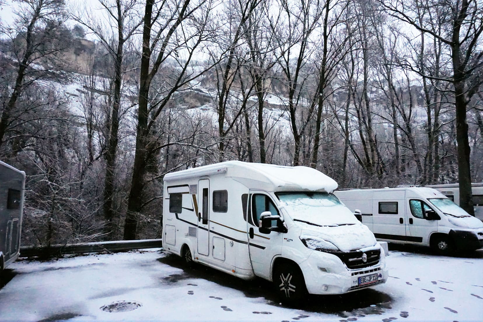 our motorhome parked in the snow in winter with bare trees behind it