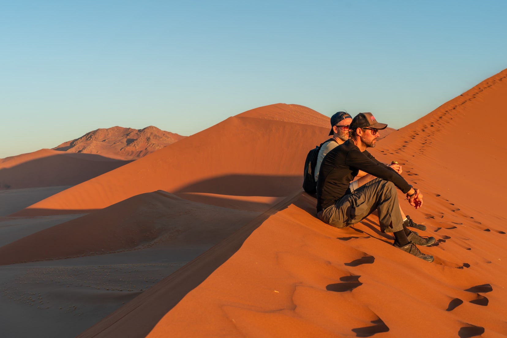Dune-45-at-sunset-with-2-guys-sitting-on-the-dune-spine,-Sossusvlei