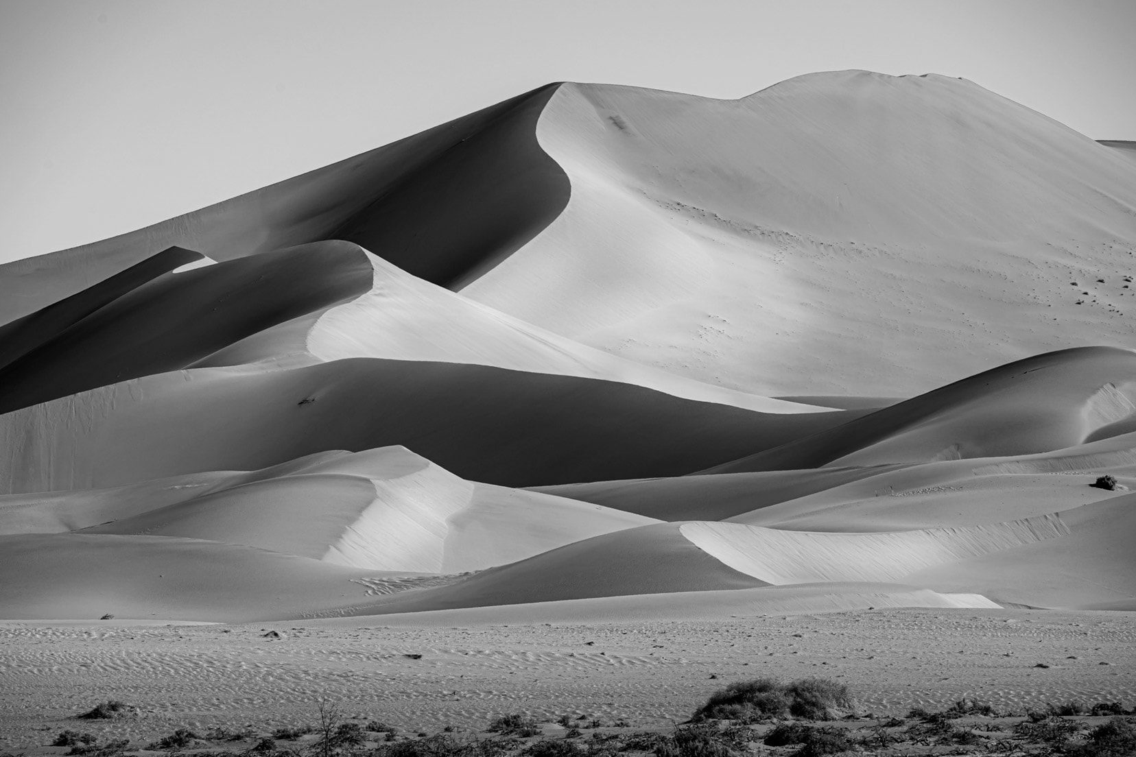 a black and white image of a wavy sand dune in Sossuvlei, Namibia