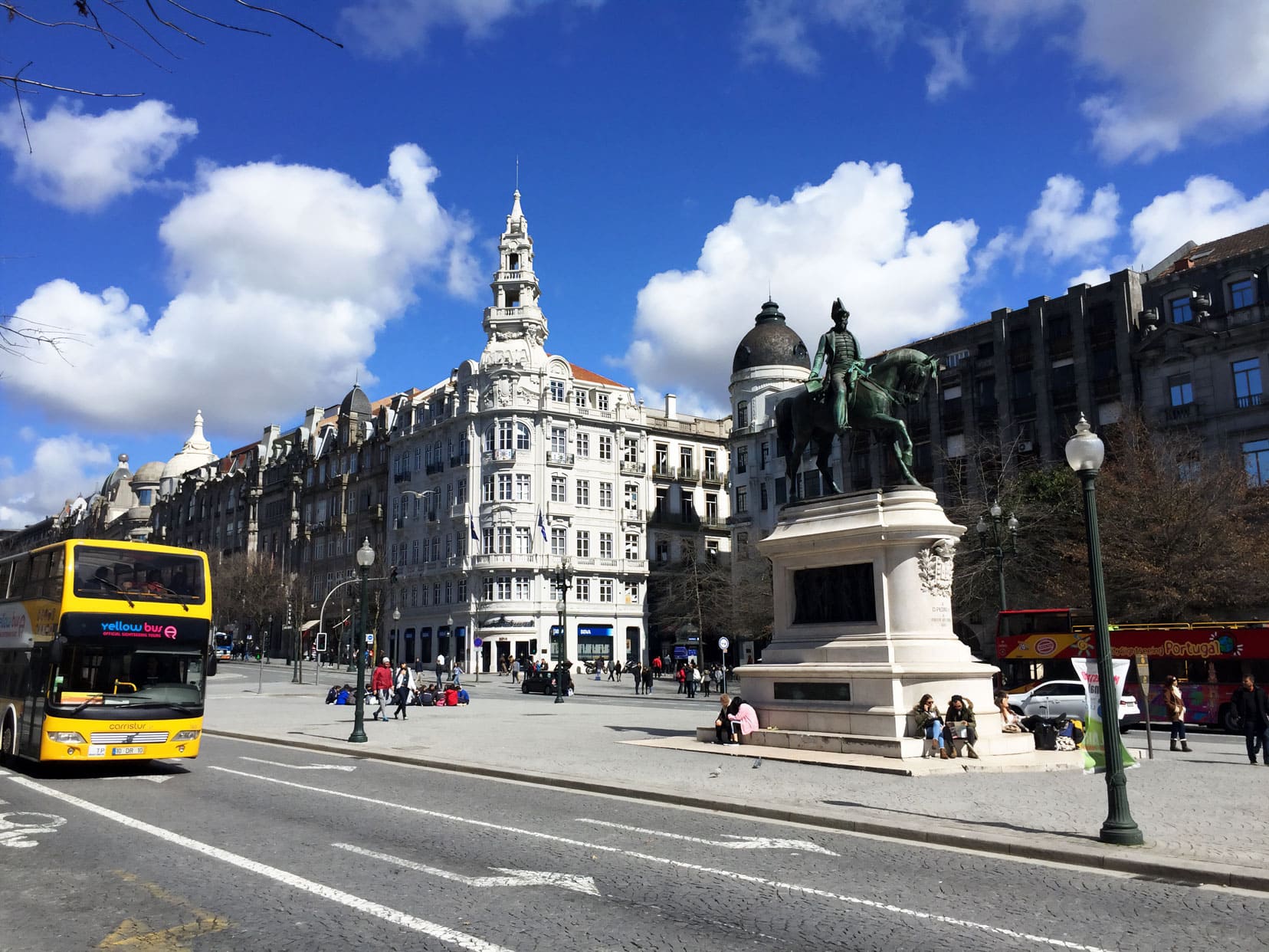 Street view of Liberty Square with statue and yellow tourist bus