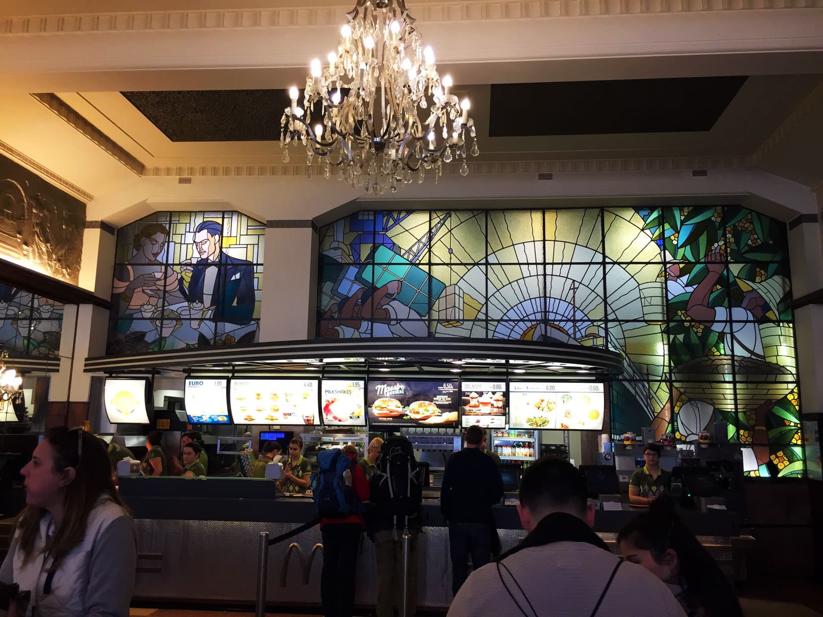 the inside of the Macdonalds burger store in Porto with a chandelier and staiened glass window back drops