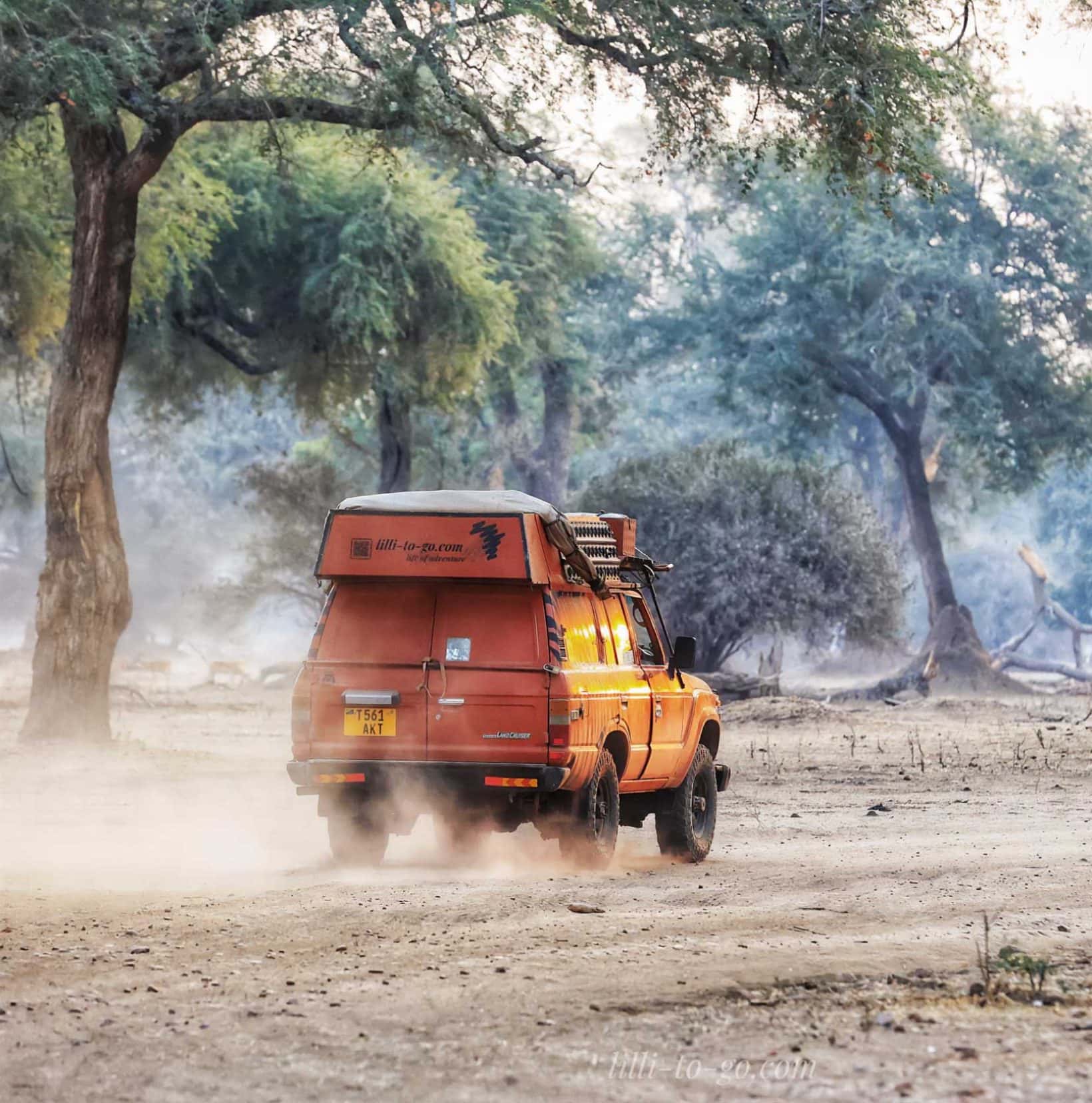 an orange Toyota driving on a dirt road 
