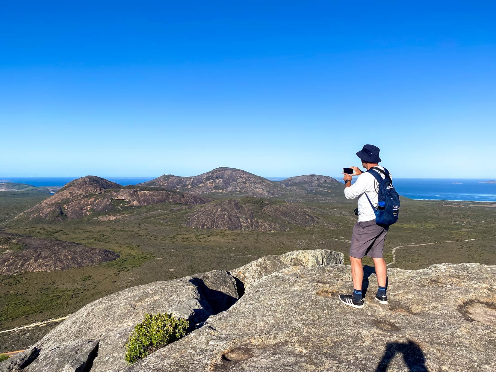 Lars on Frenchman Peak taking a video with an iphone with views across cape le grand and the ocean