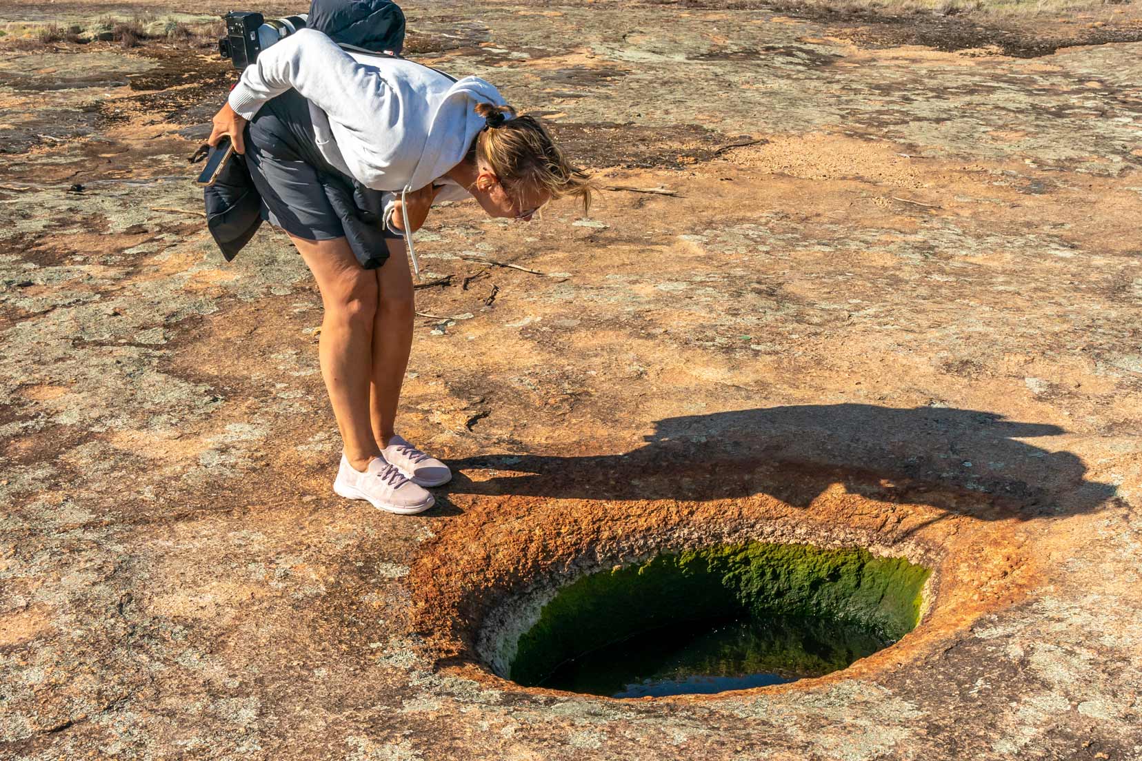 Shelley peering in to a gnamma hole - a natural well in rock