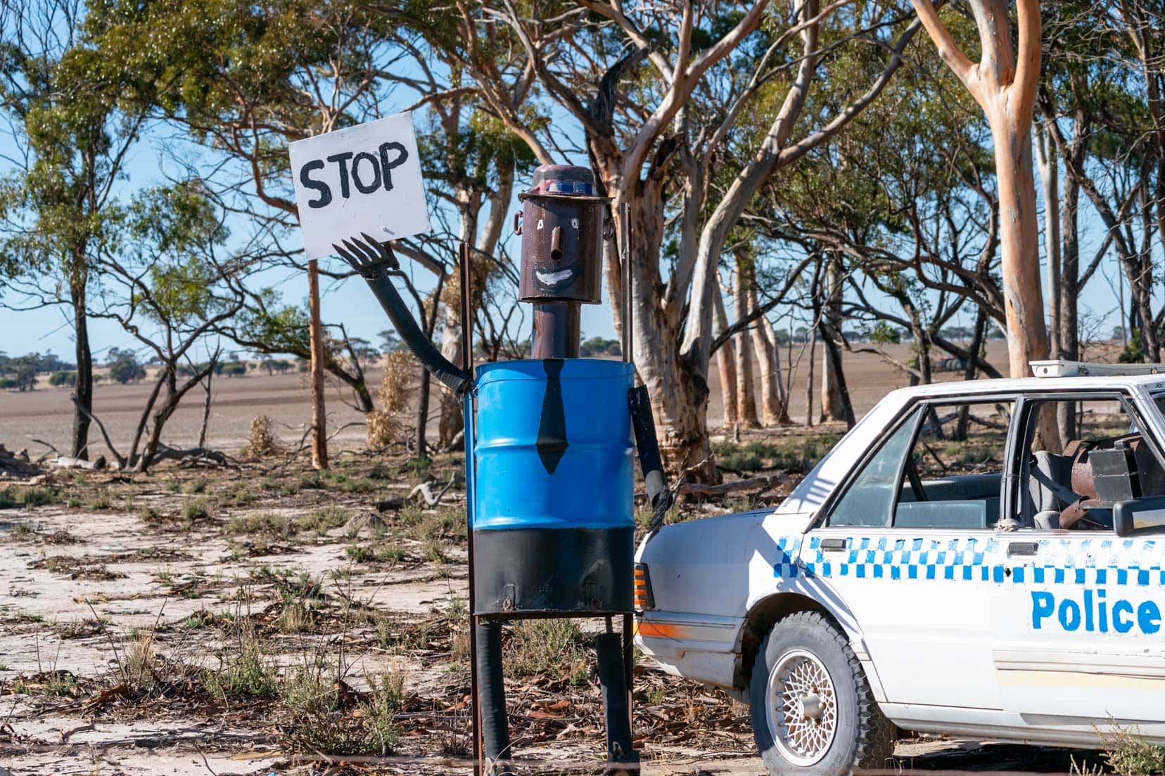 Policeman tin horse holding a sign that says stop by an old police car
