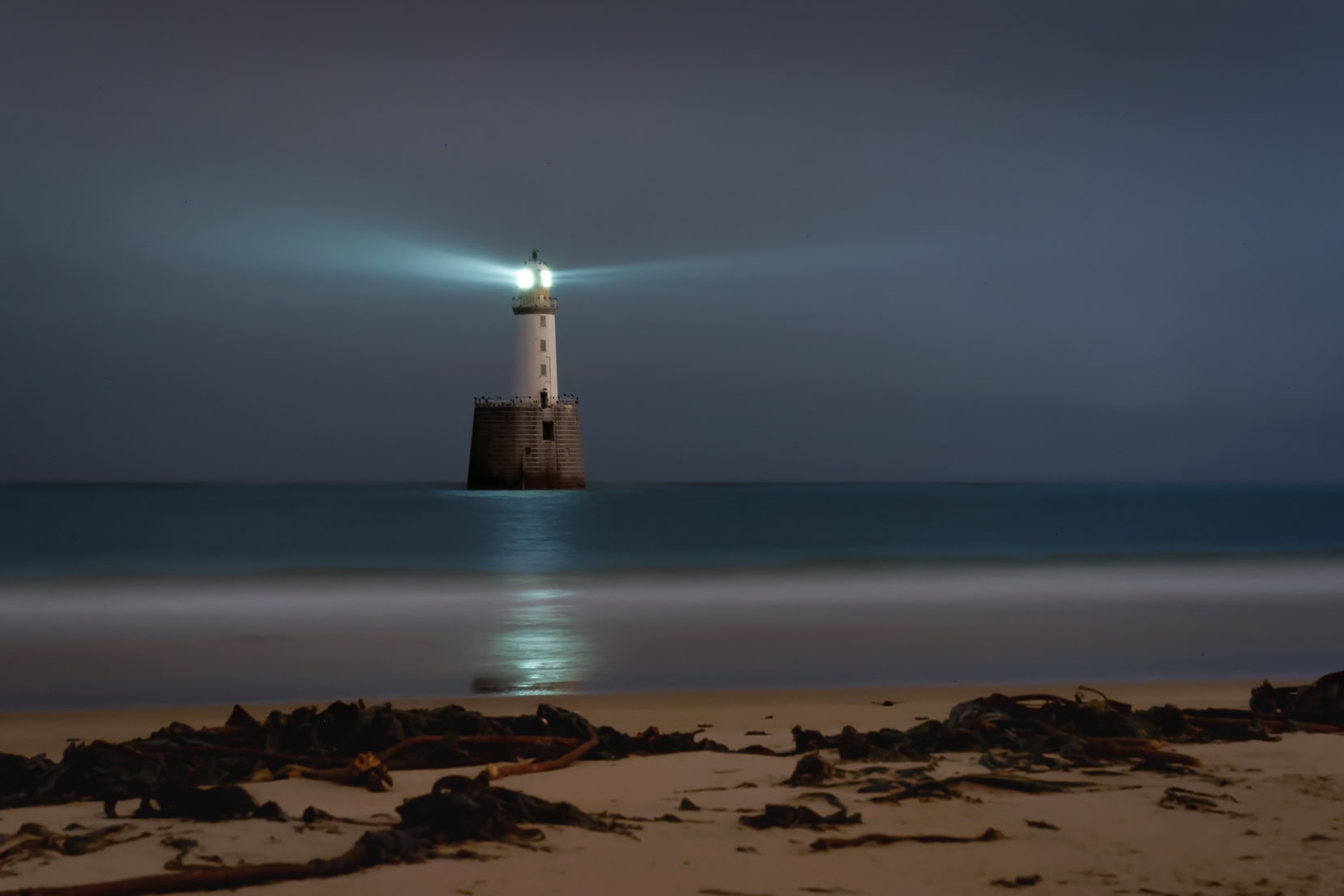 Rattray-Head-Lighthouse,-Scotland just before dawn with the lighthouse light making an impact 