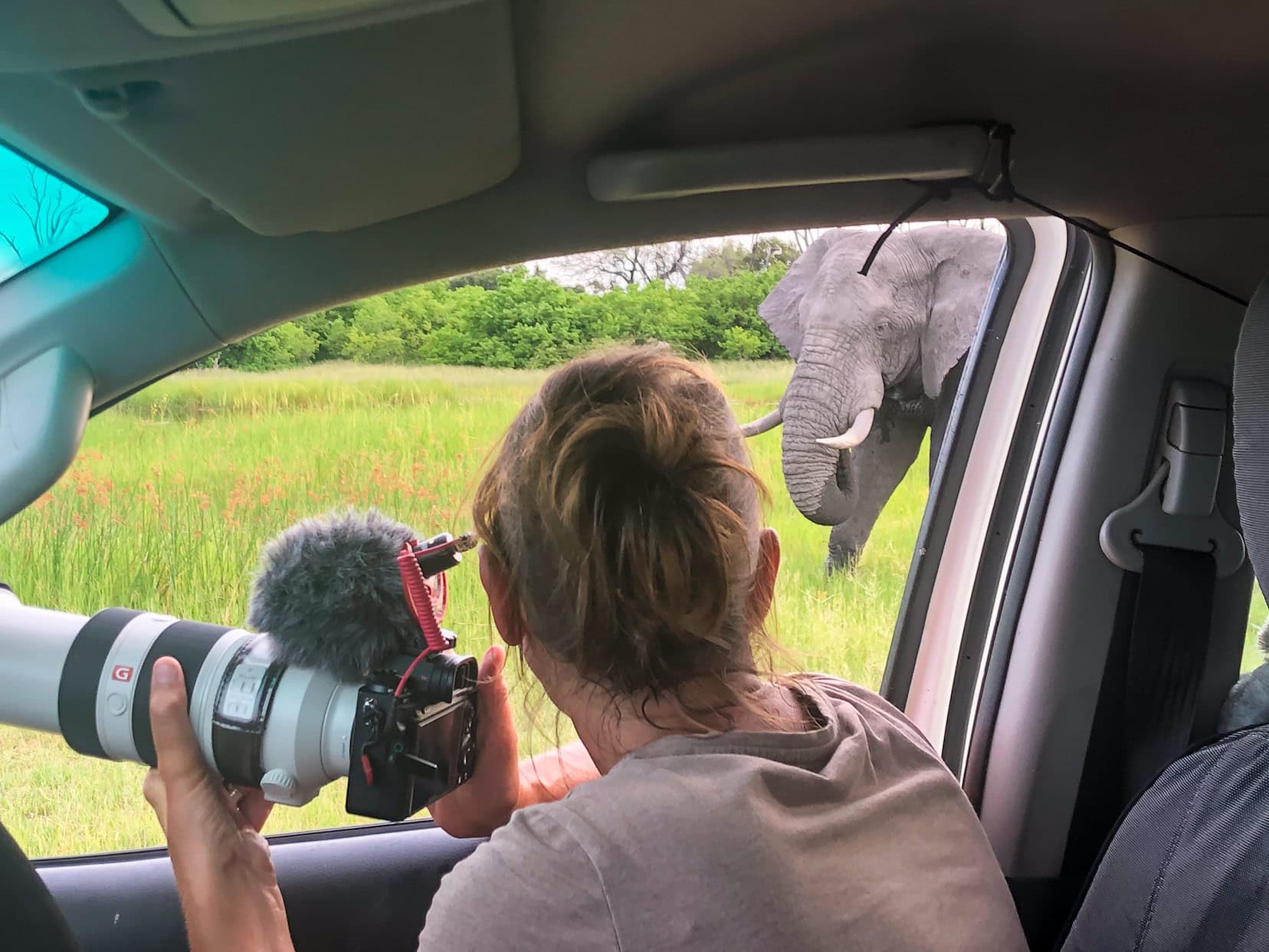 Shelley sat in car with camera in hand on a road trip in Khwai, Botswana 