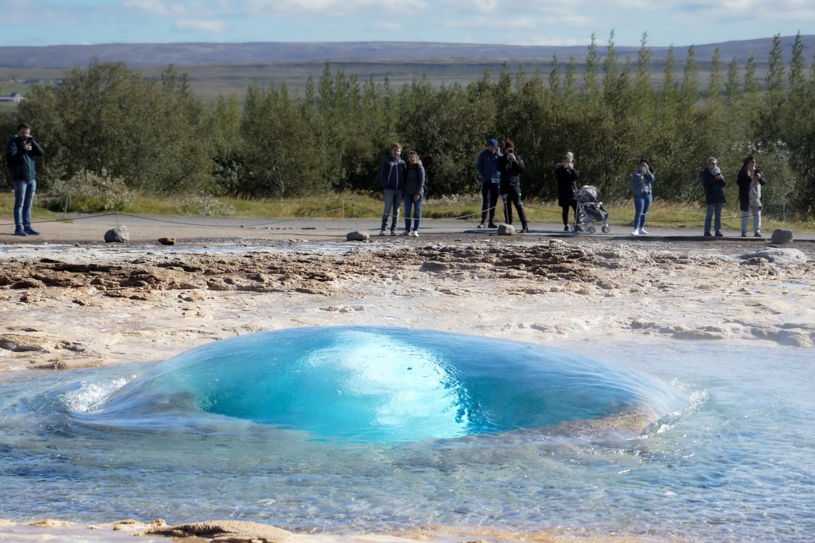 A huge geysir about to erupt it looks like a blue bubble rising out of the ground