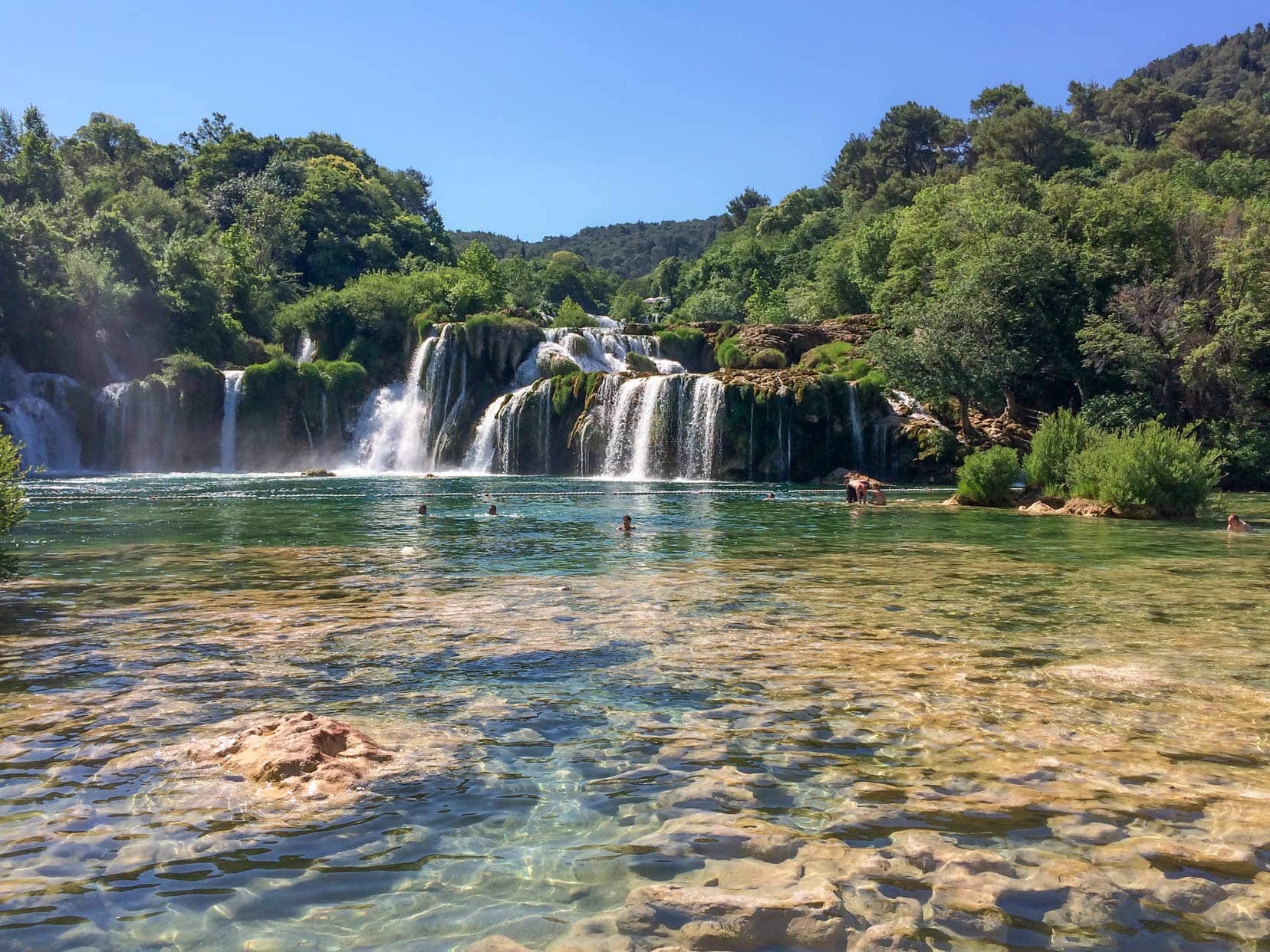 Krka Waterfall crystal clear water and lush greenery around a lengthy waterfall