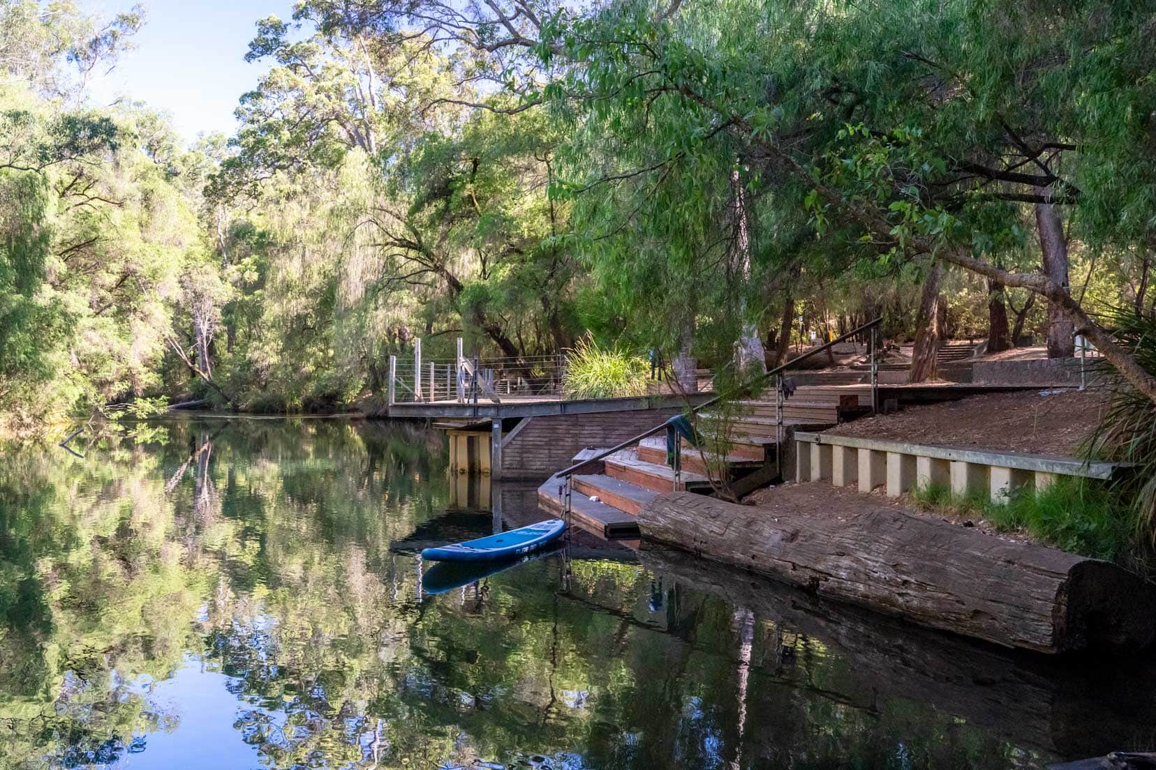 Honeymoon-Pool-the-water surrounded by trees with a sup board by the jetty