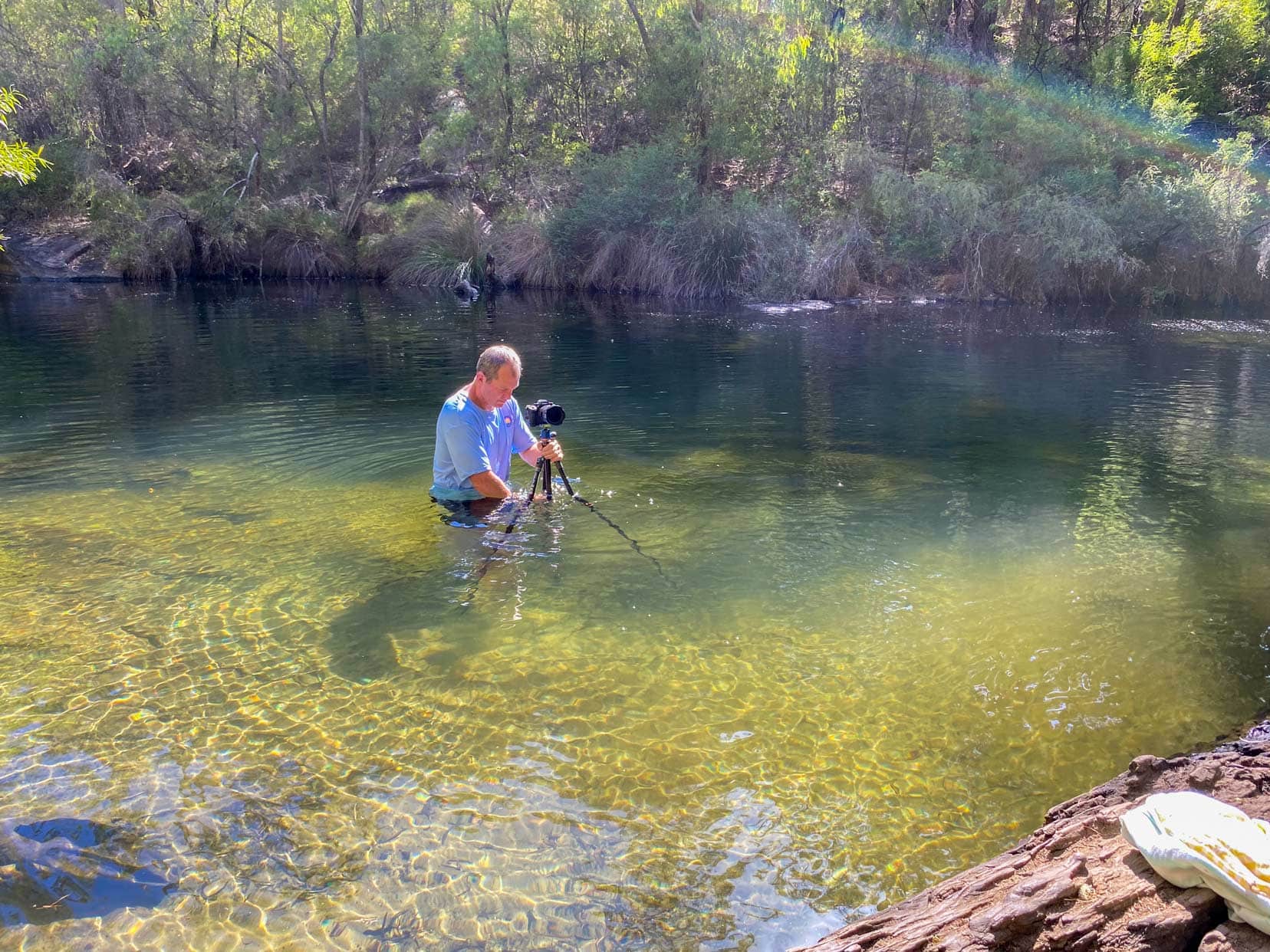 Lars setting up his camera on the tripod in the river 