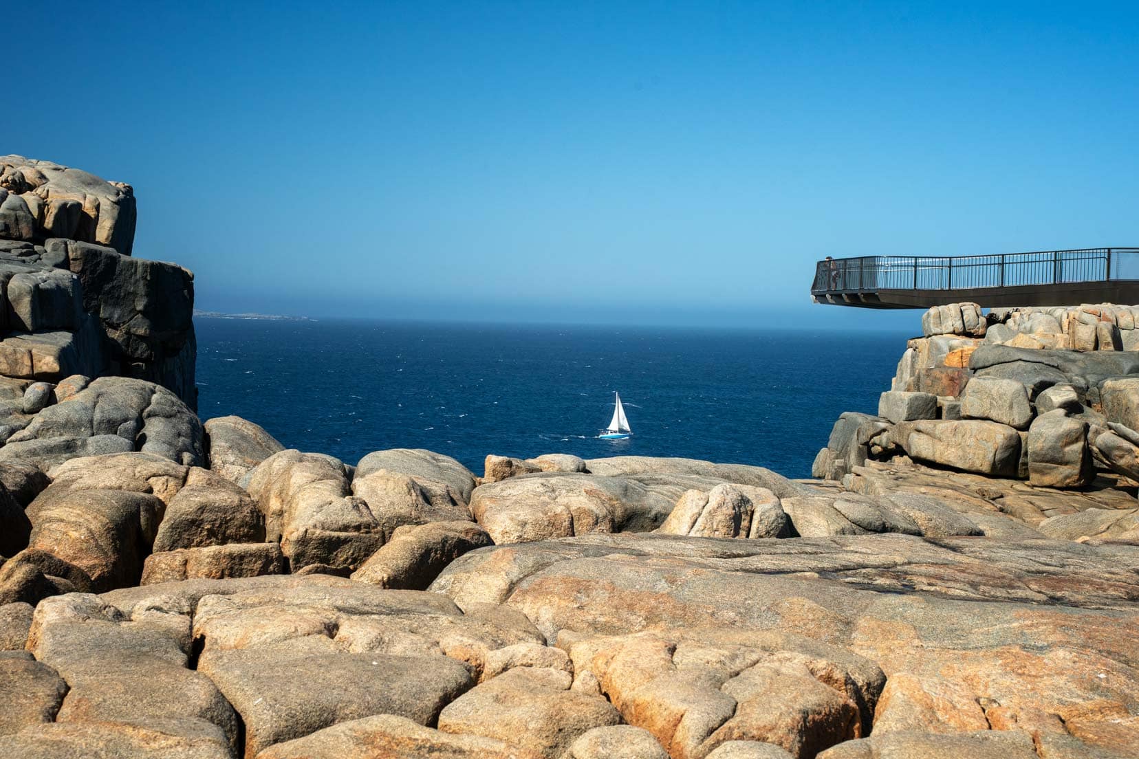 Perth-to-Esperance-Road-The-Gap-and-Natural-Bridge-Torndirrup - view of part of the lookout and the ocean in the background with a sailboat sailing by 