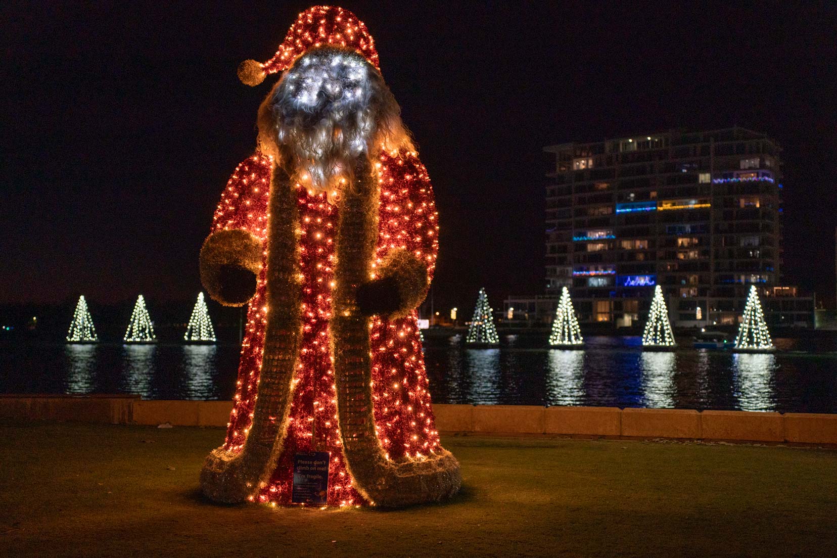 Perth-to-Esperance-Road-Trip-Mandurah-Christmas-Lights - a santa lit up with white christmas trees lit up on the river 