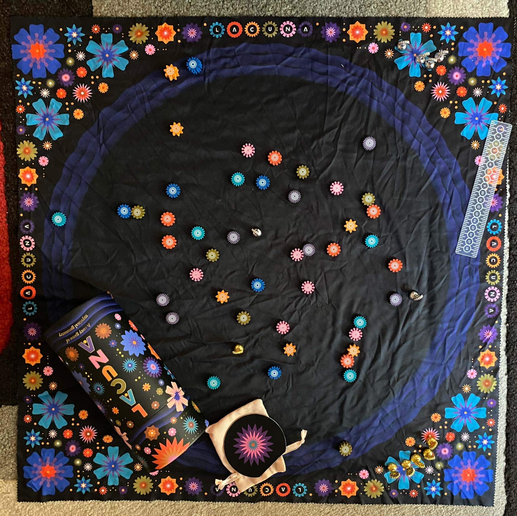 Birds eye view of lacuna mat and playing pieces which are coloured flowers 