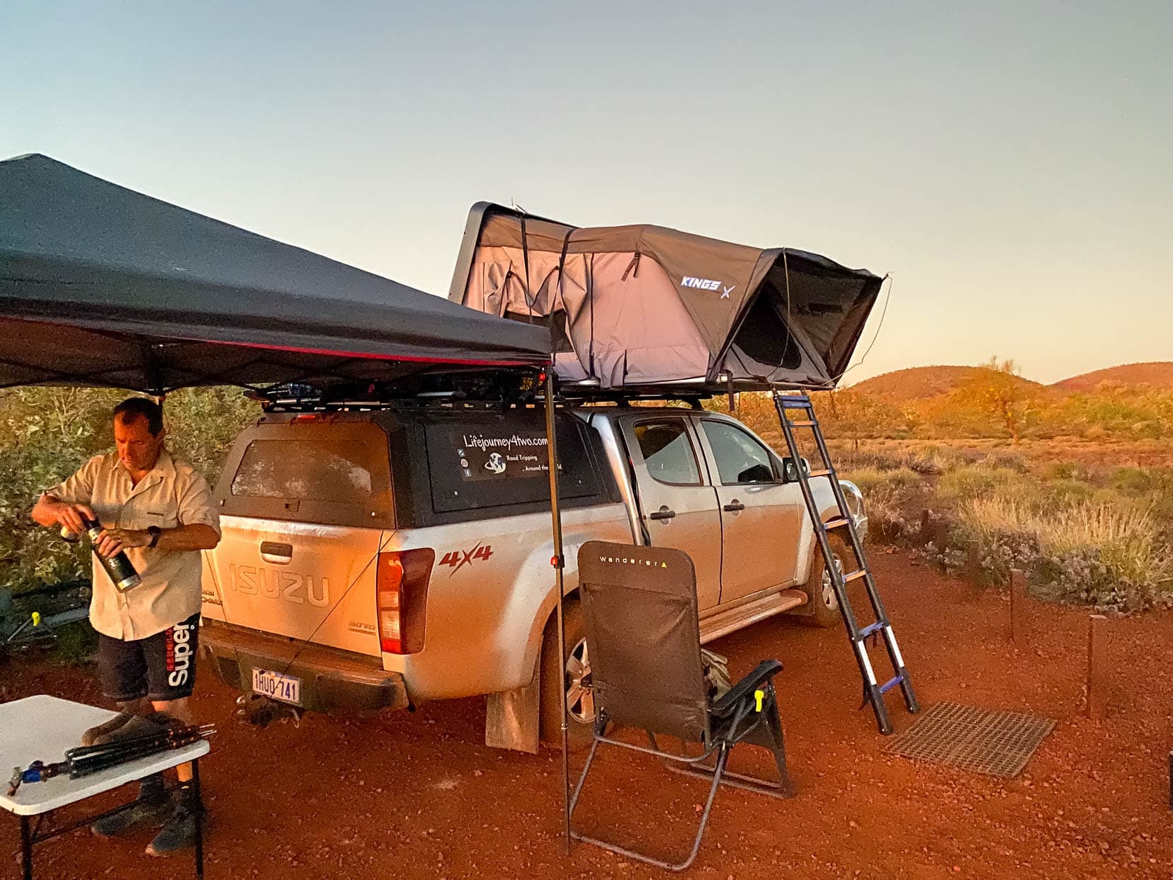 Our car with roof top tent set up showing ladder and a  cabana set up over the back of the car