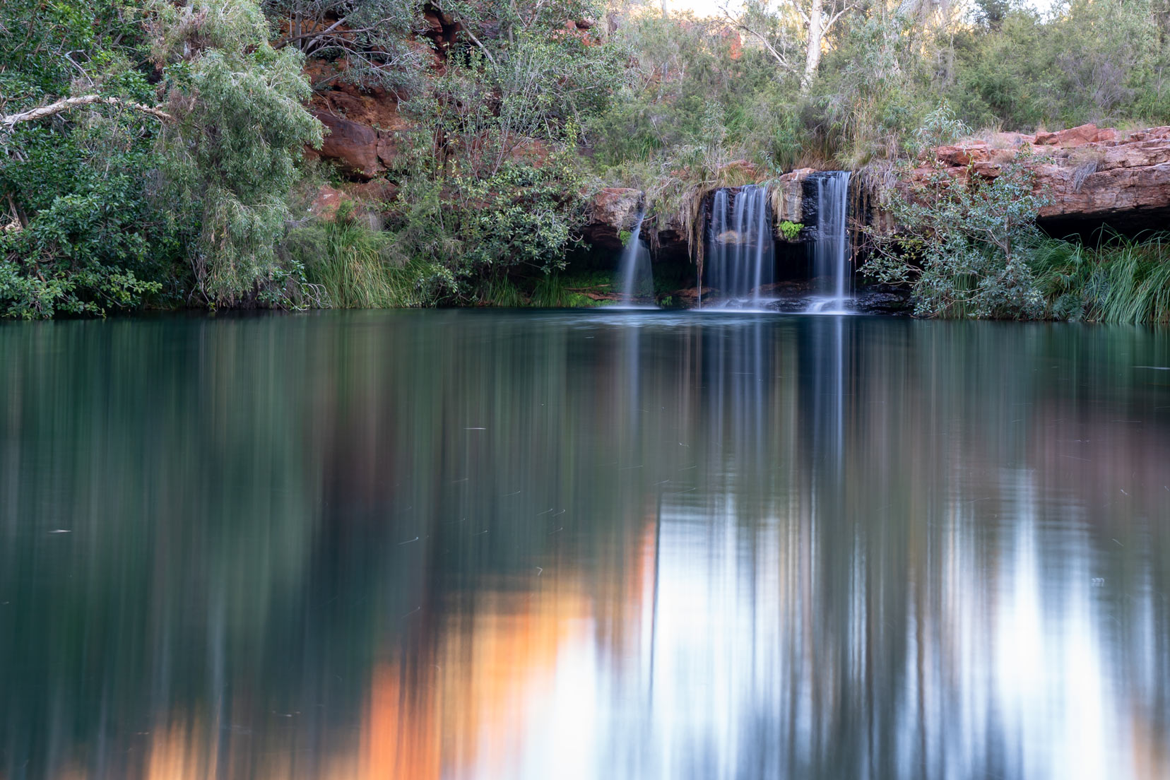 Fern Pool Dales Gorge - the waterfall at the end of the pool and orange reflections of the rock on the water