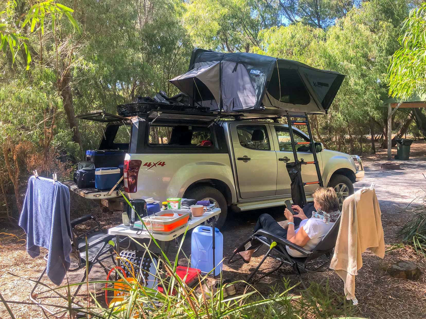 Camping in WA Coalmine Camp, Walpole with shelley sat on a camping chair by the car with roof top tent 